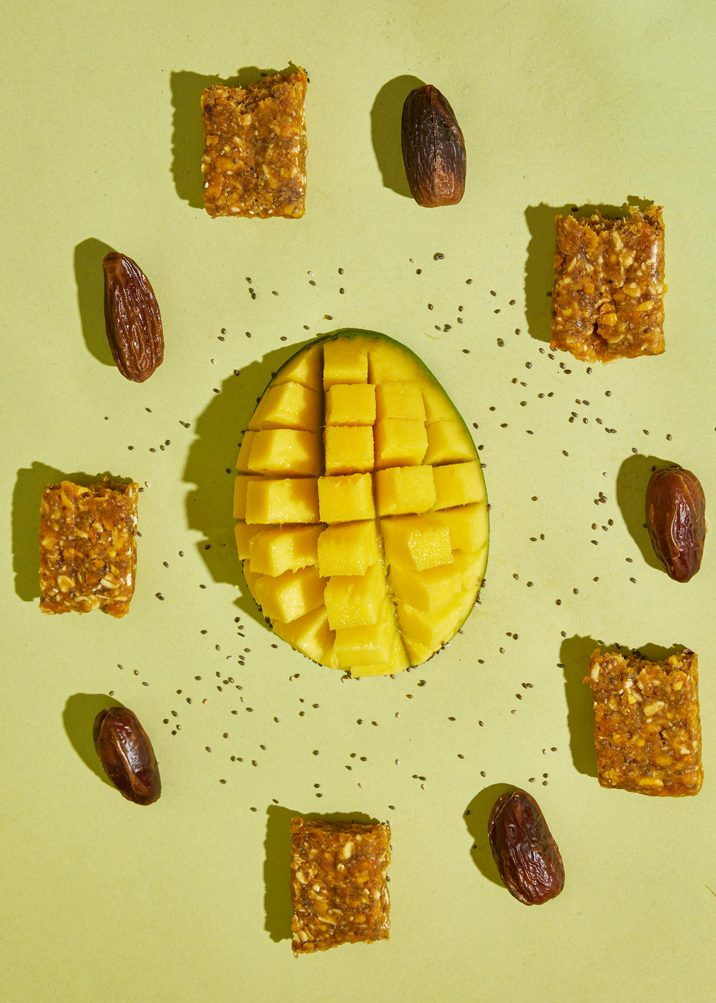 eine mangoscheibe , die in stücke geschnitten wird , umgeben von datteln und anderen snacks