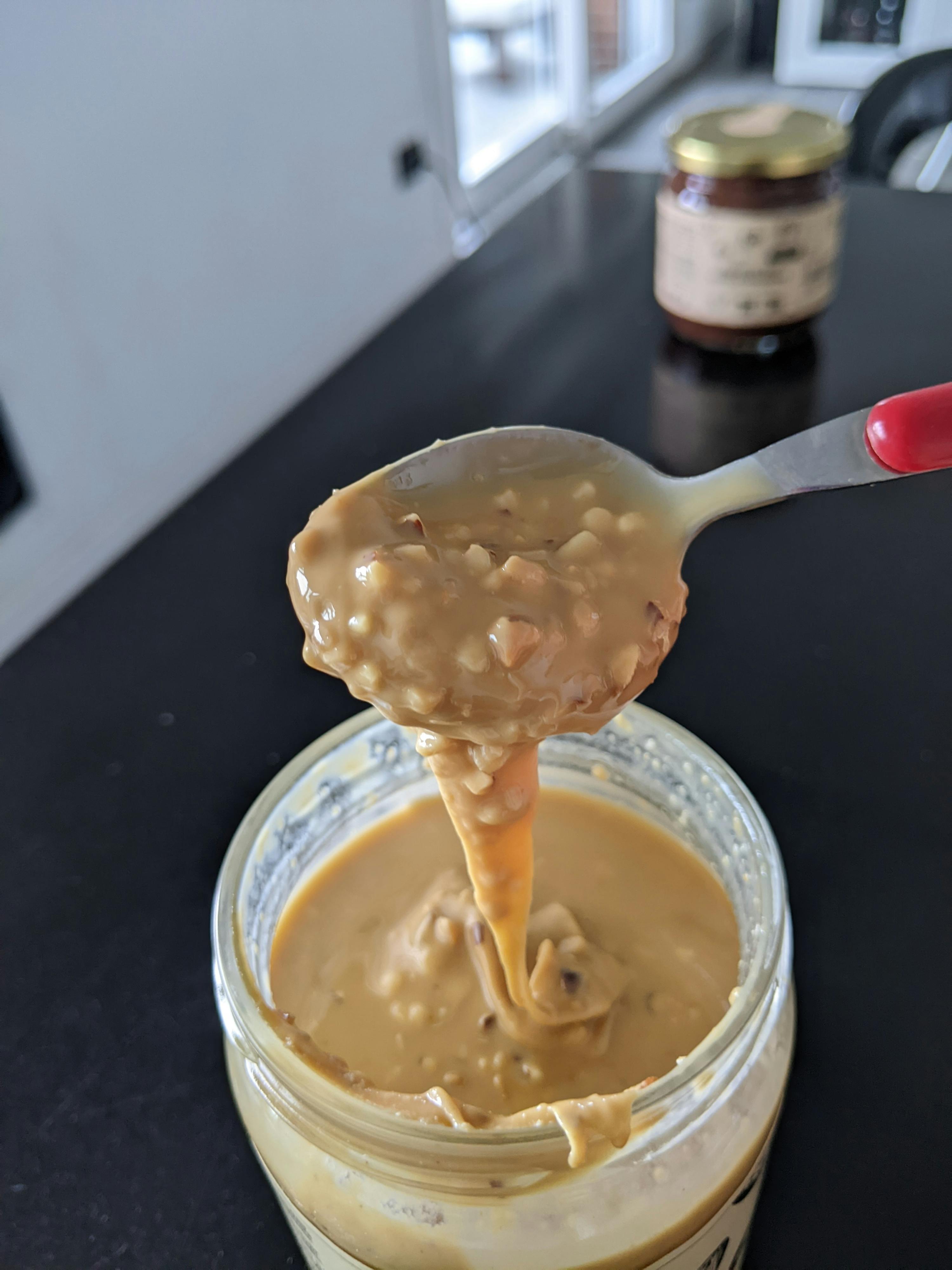 une cuillère remplie de beurre d' arachide est prise d' un bocal