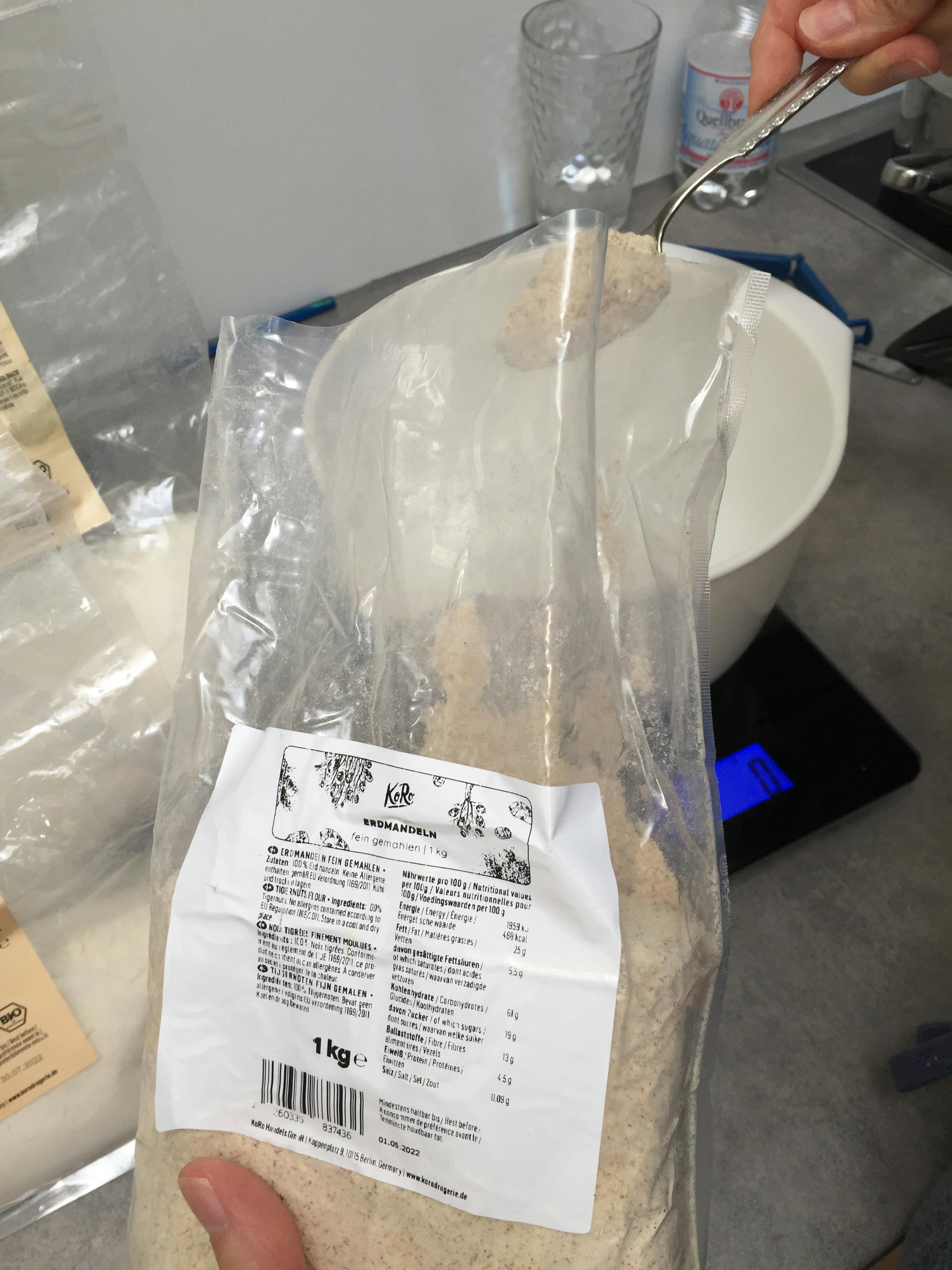 une personne tient un sac de farine de 1 kg à côté d' un bol