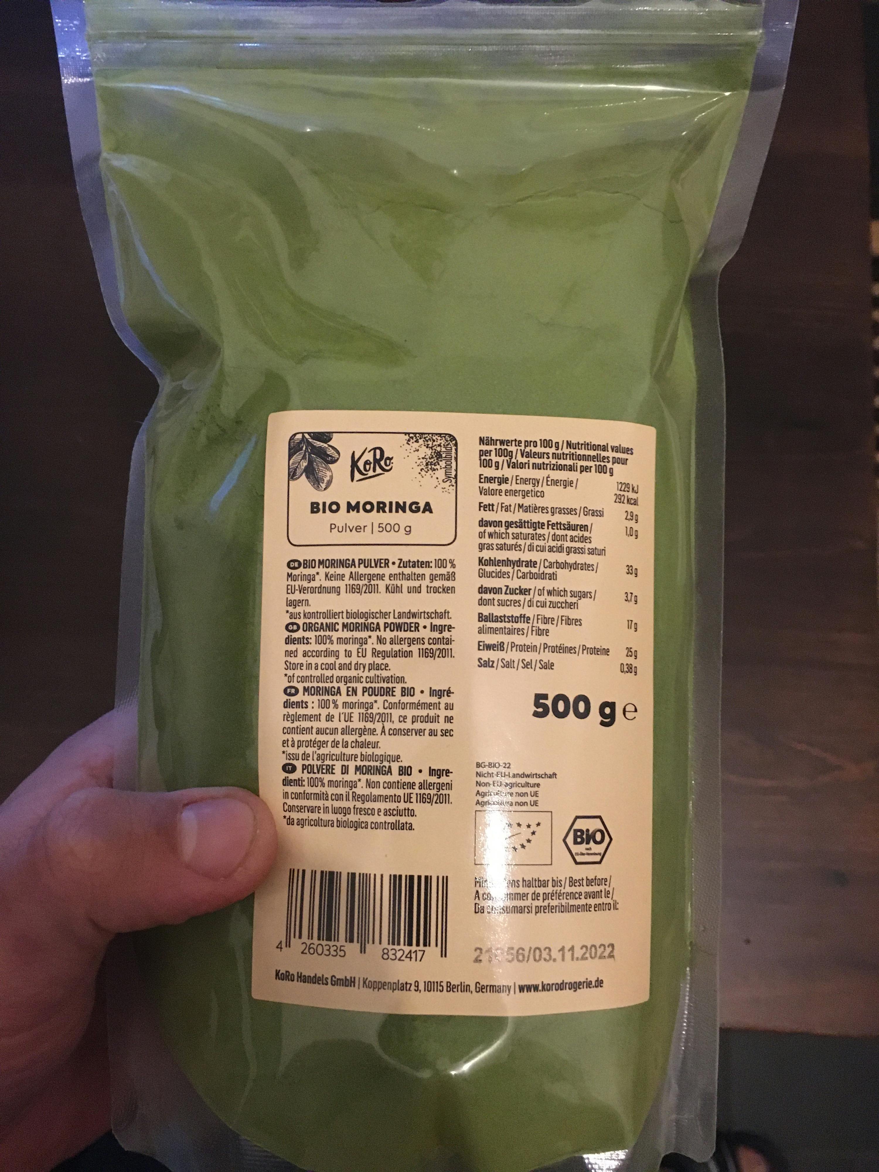 une personne tient un sac de moringa bio 500 g