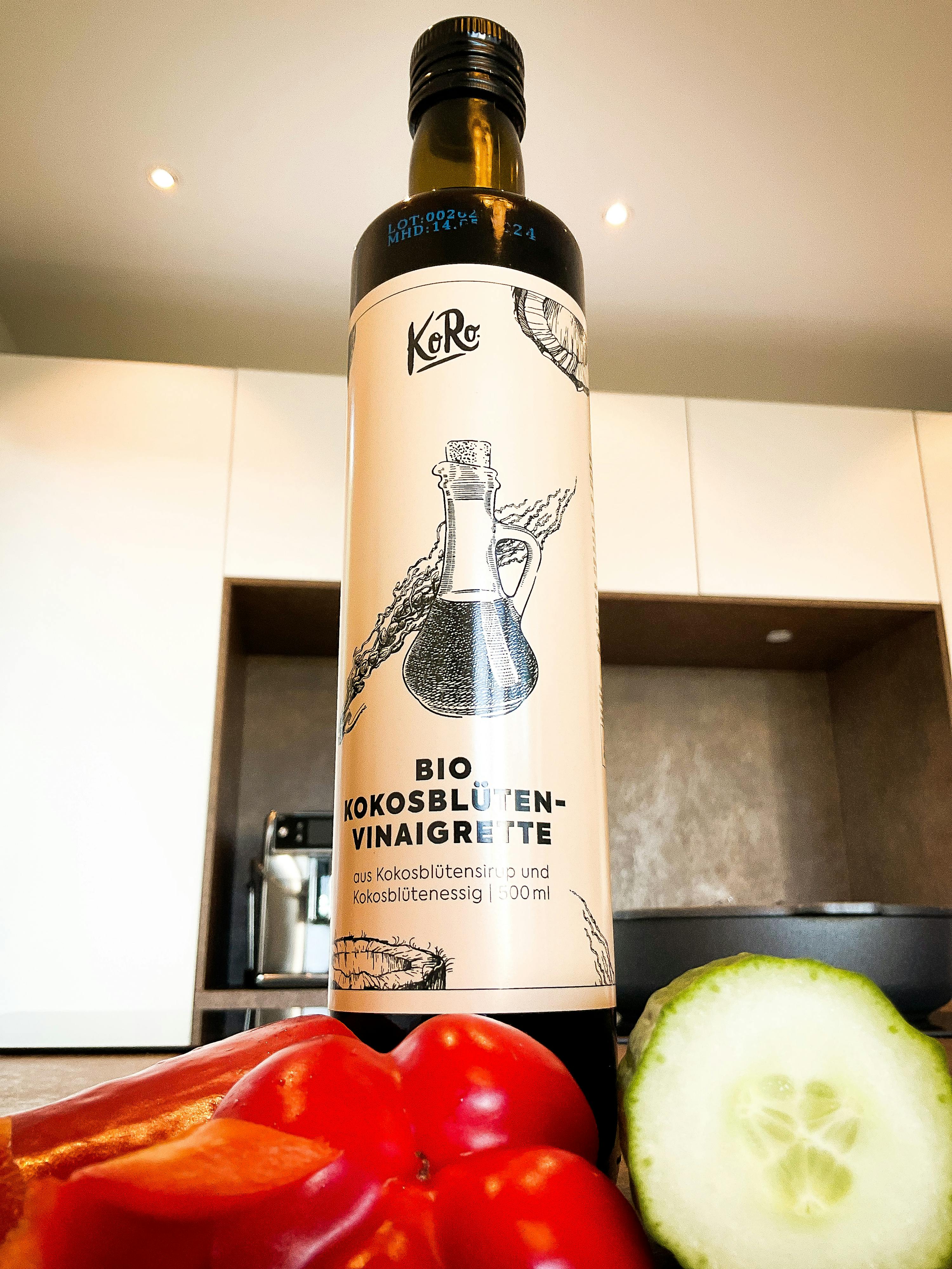 une bouteille de vinaigre de noix de coco bio est posée sur un comptoir avec des légumes