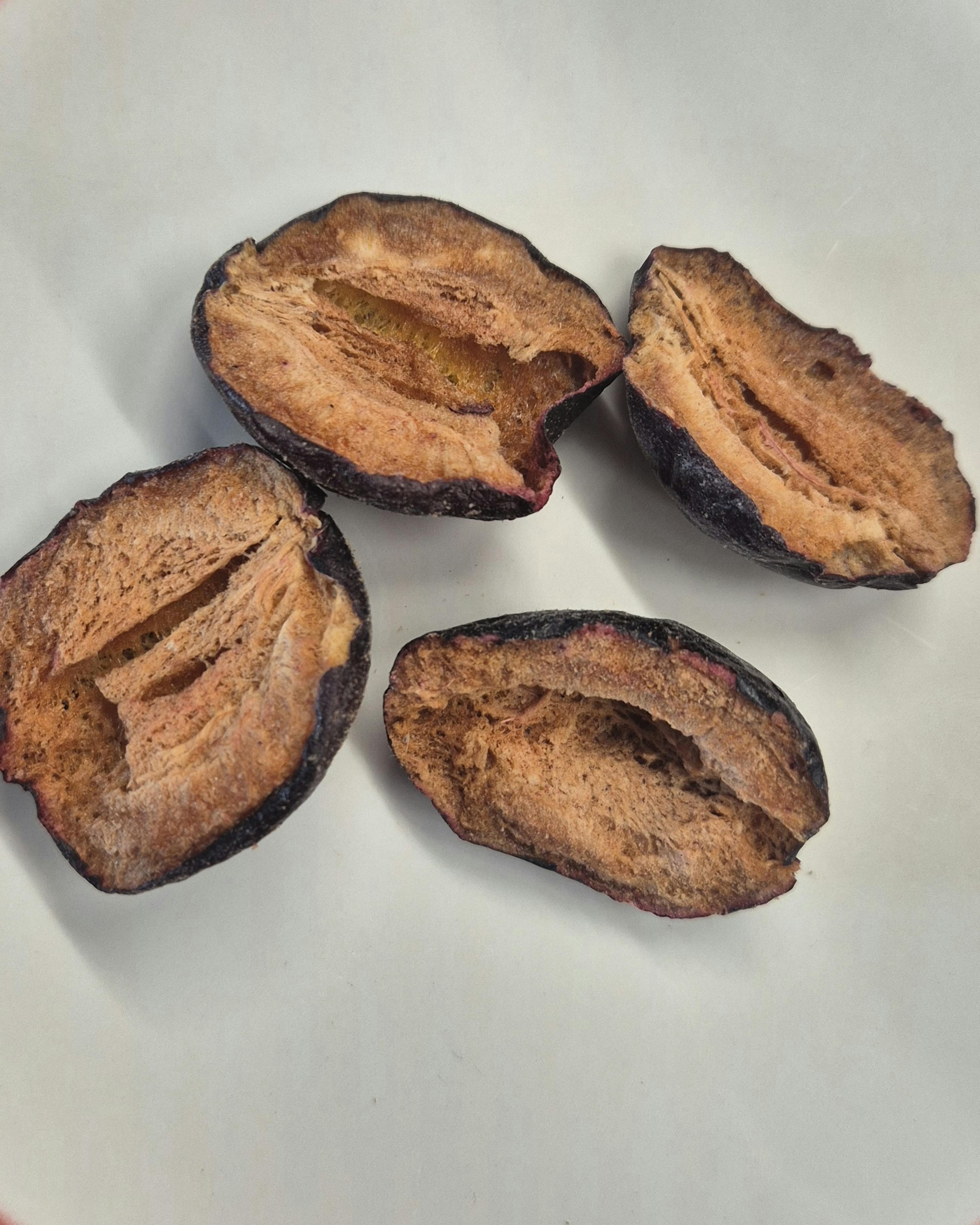 a white plate topped with four sliced plums with a hole in the middle