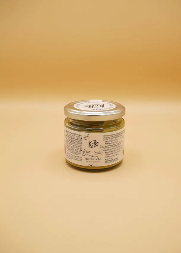 un bocal de crème de pistache est posé sur un fond beige