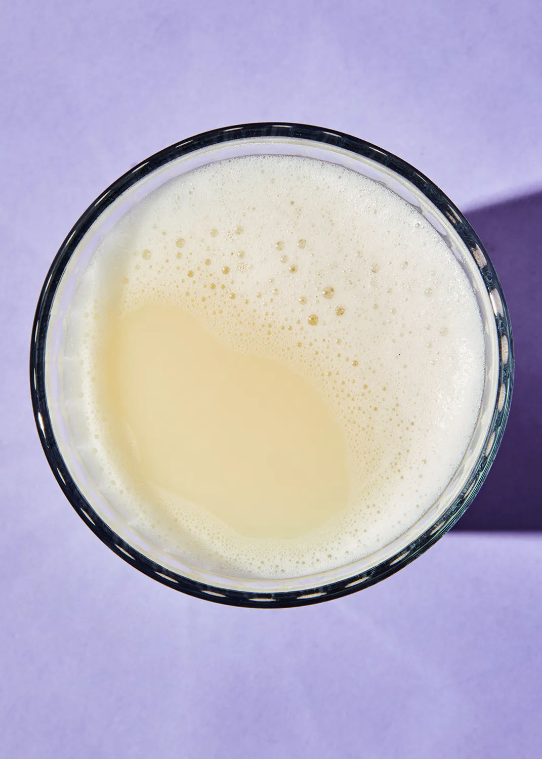 un gros plan d' un verre rempli de liquide sur fond violet