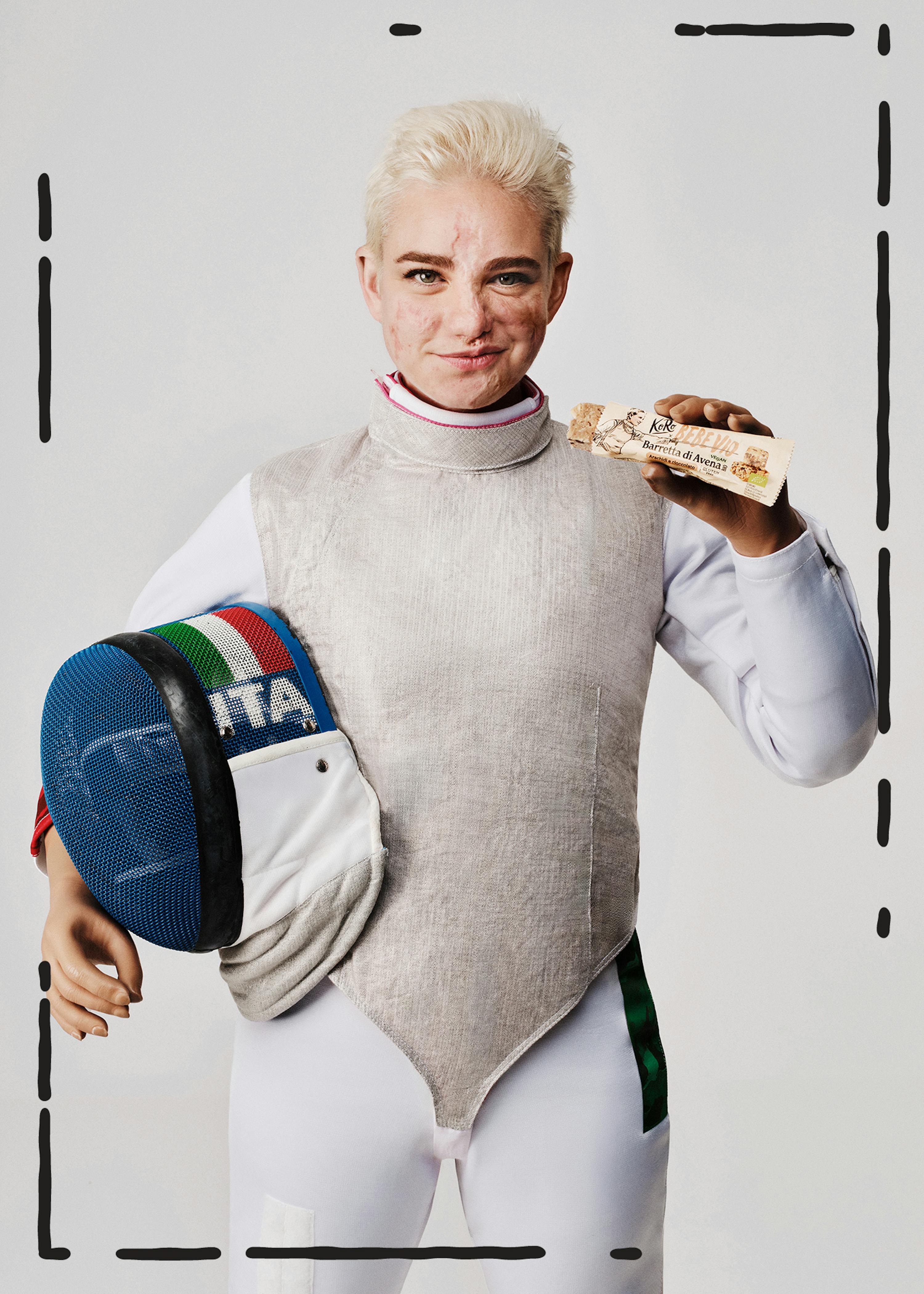 una donna in abito da scherma tiene in mano una barretta di frutta