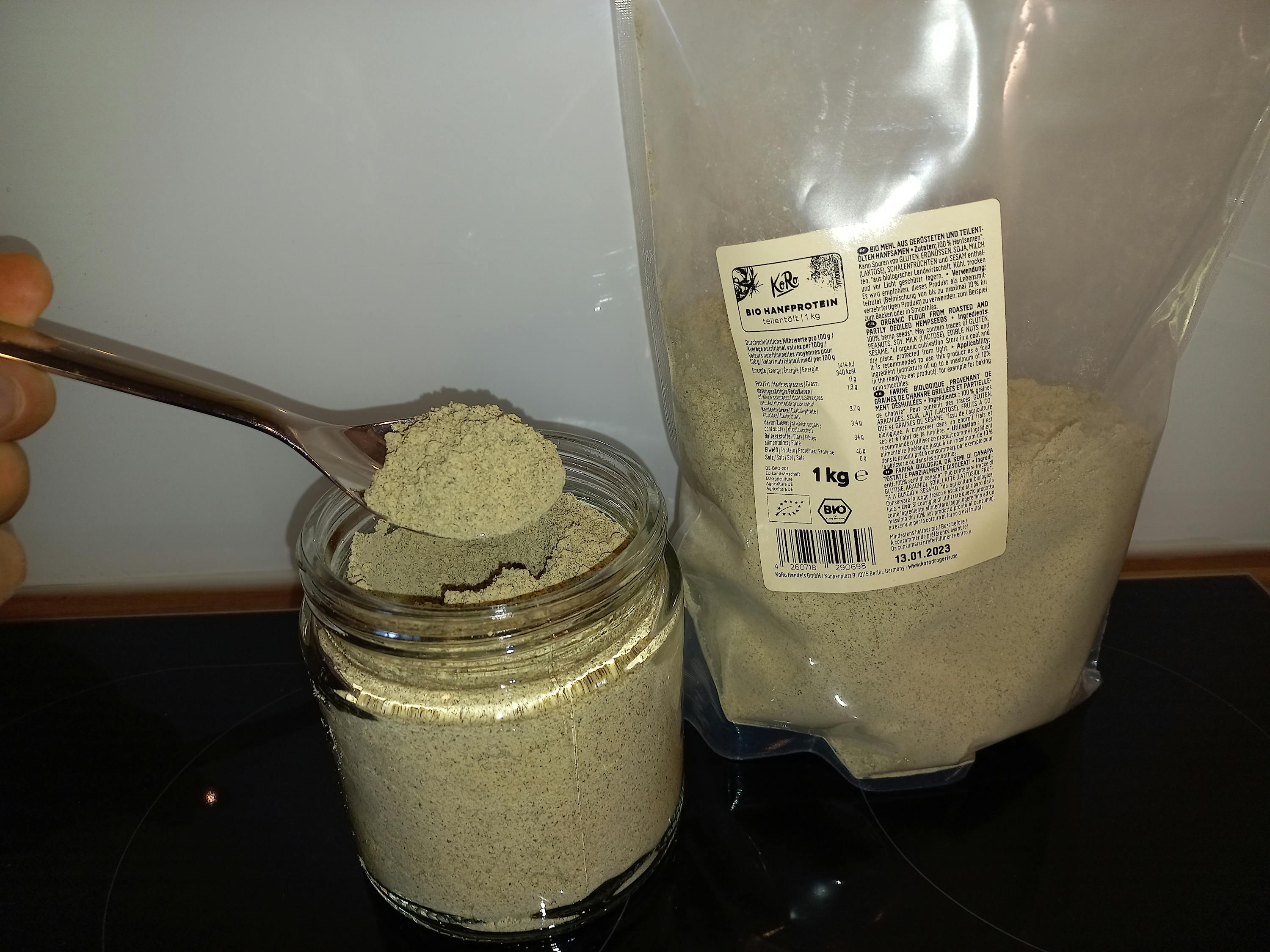 un cucchiaio di polvere viene versato in un barattolo accanto a un sacchetto di polvere bio