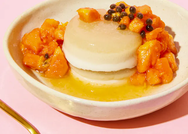 un gros plan d' un bol de nourriture sur une table rose avec une cuillère