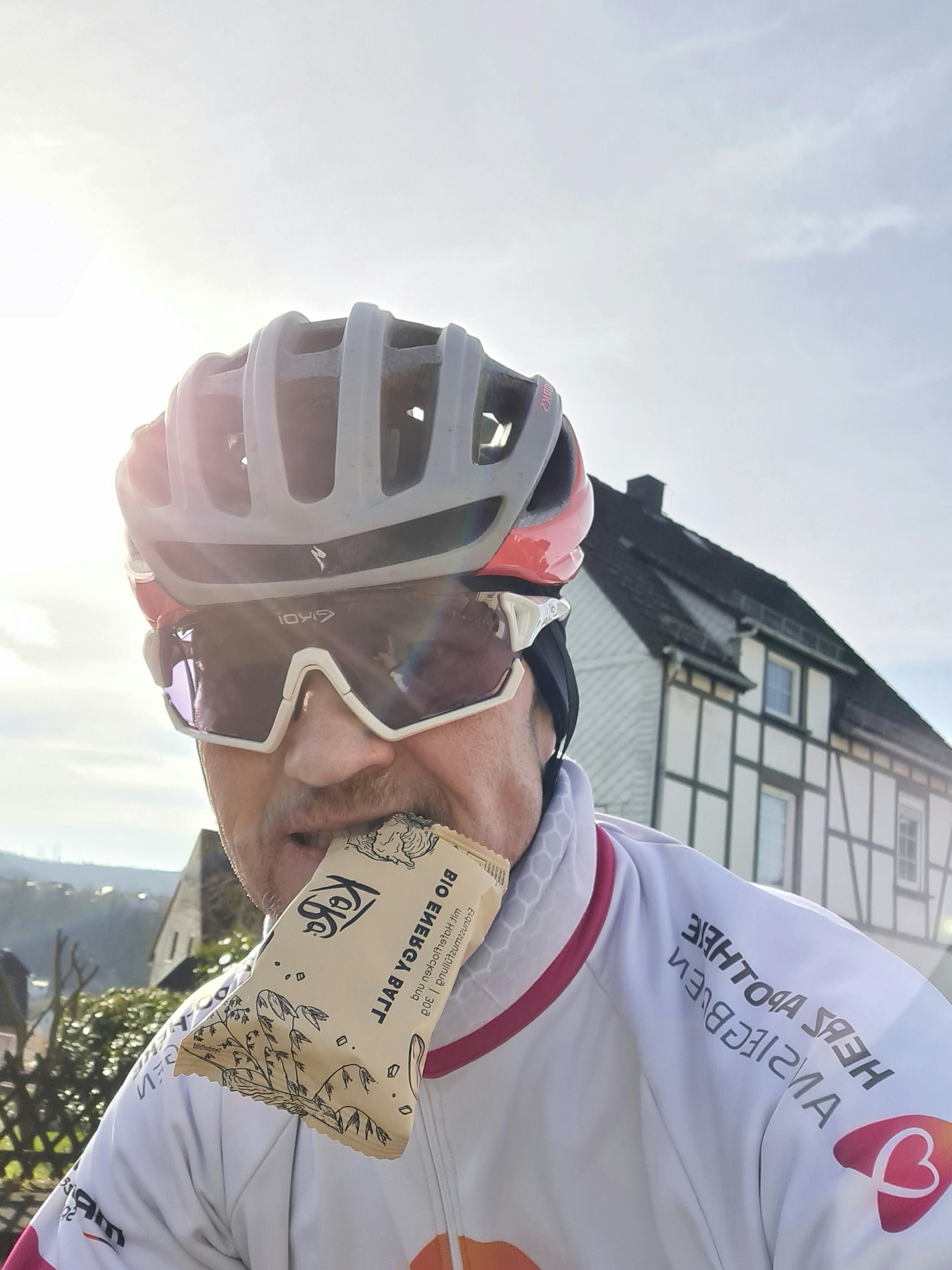 ein mann hält einen fahrradhelm in der hand und trägt ein fahrradtrikot mit einem herz darauf