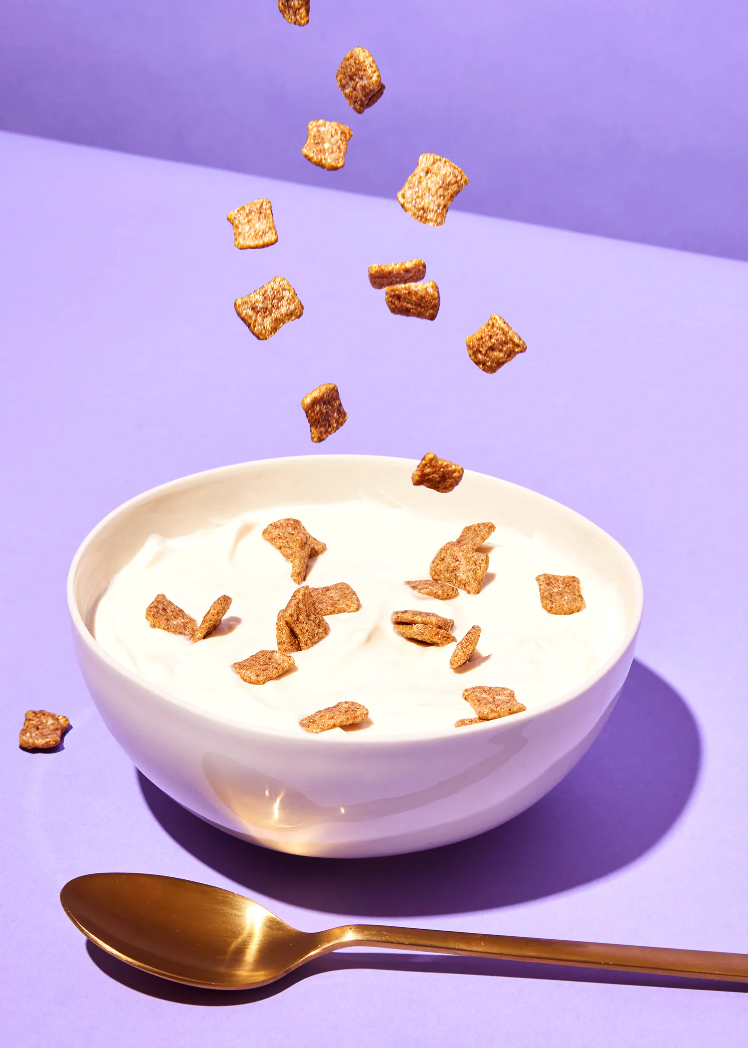 des céréales tombent dans un bol de yogourt et une cuillère