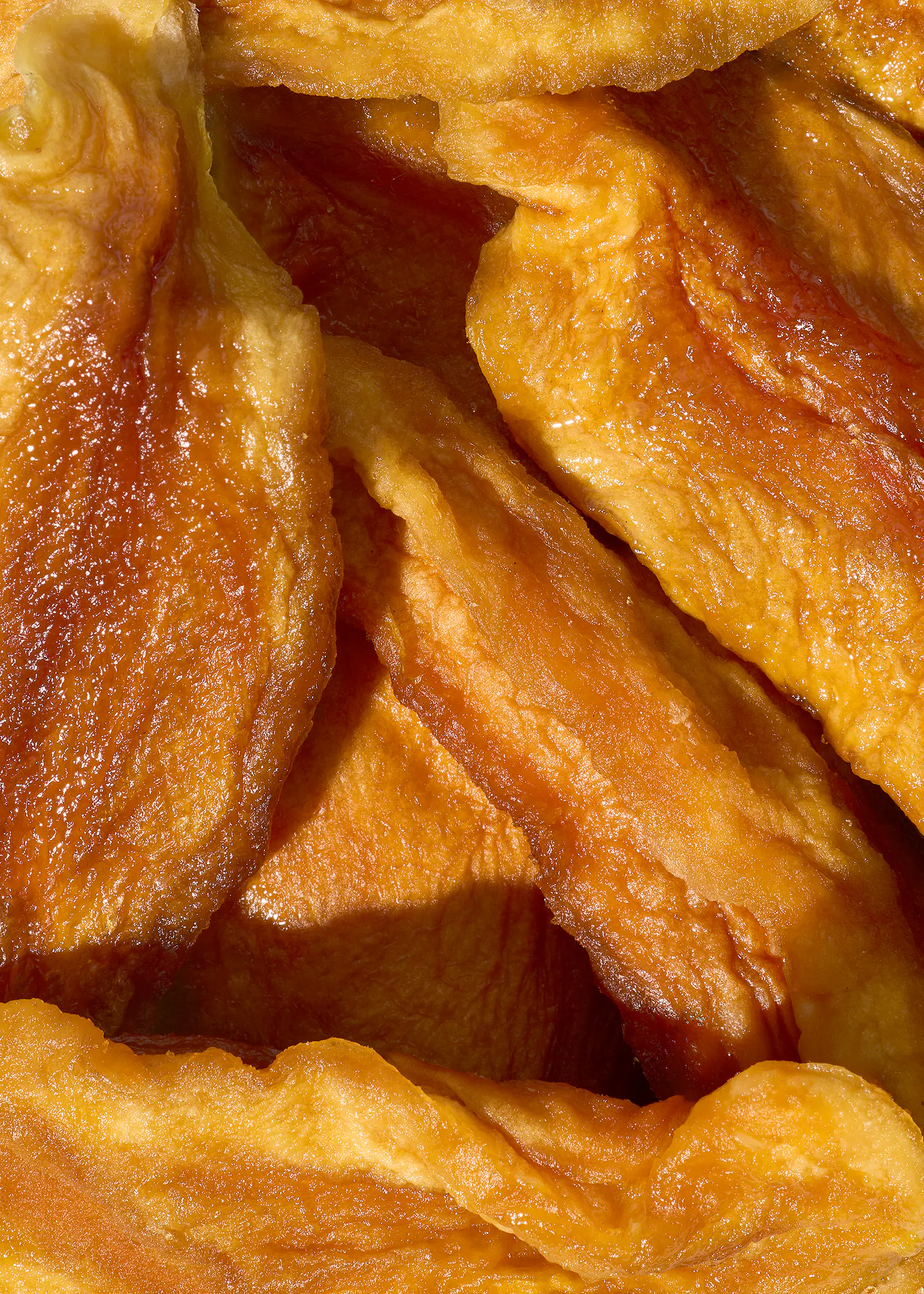 a close-up of golden-orange dried fruit slices with a glossy, wrinkled texture.