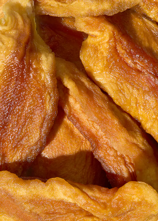 a close-up of golden-orange dried fruit slices with a glossy, wrinkled texture.
