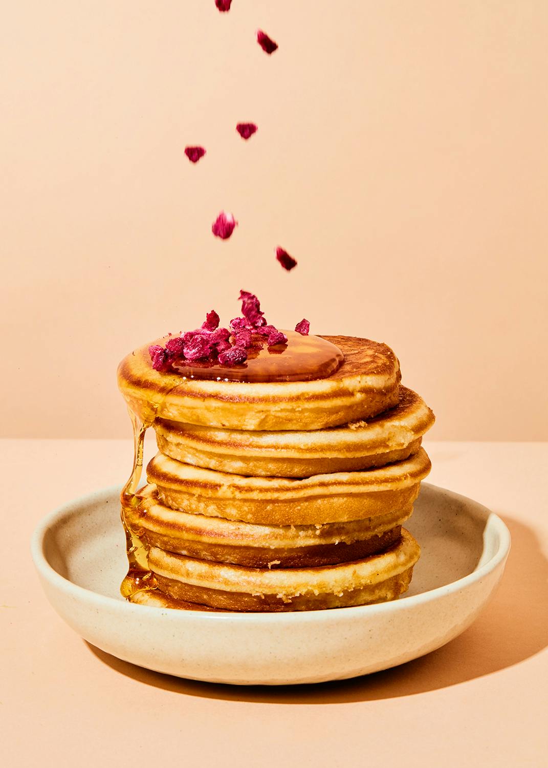 a stack of pancakes with syrup and berries on top