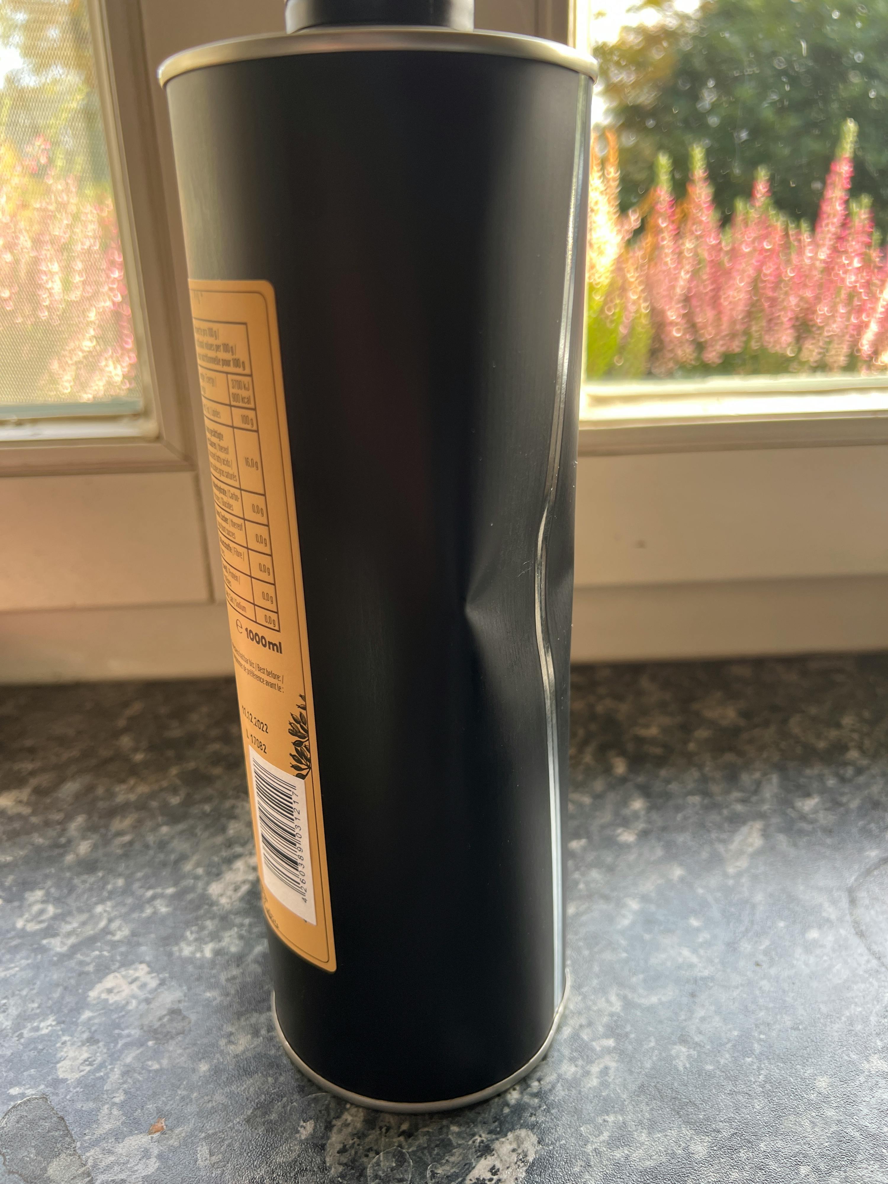 eine schwarze Dose mit einem gelben Aufkleber steht auf einem Tisch vor einem Fenster