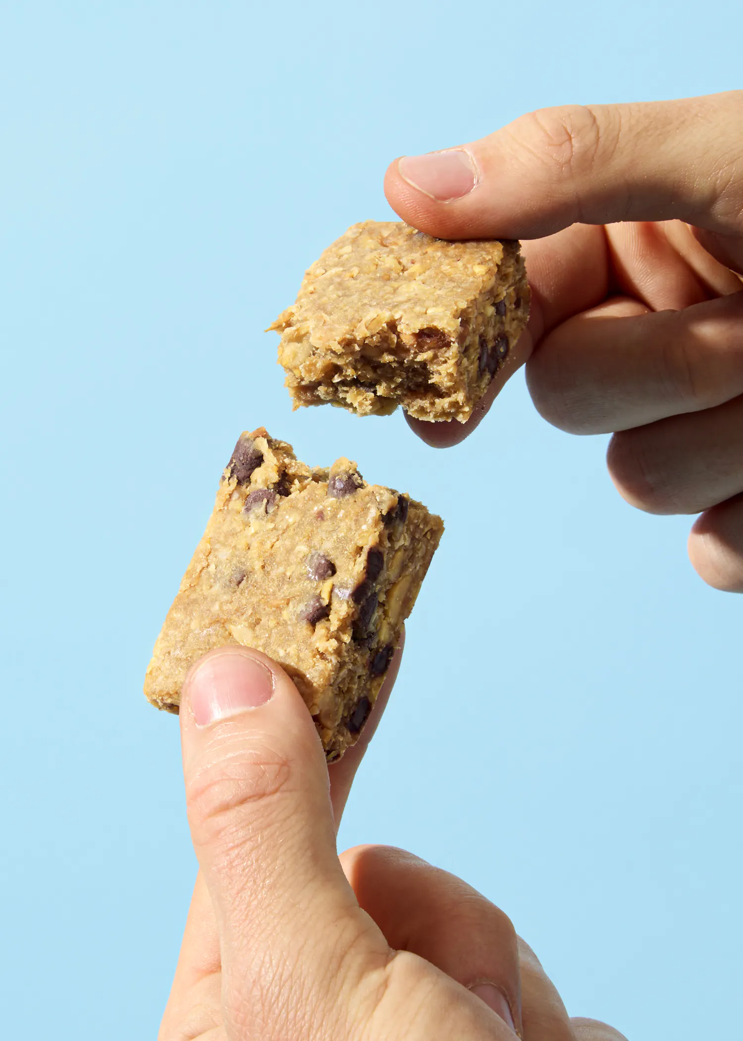 a person holding a cookie bar with a bite taken out of it