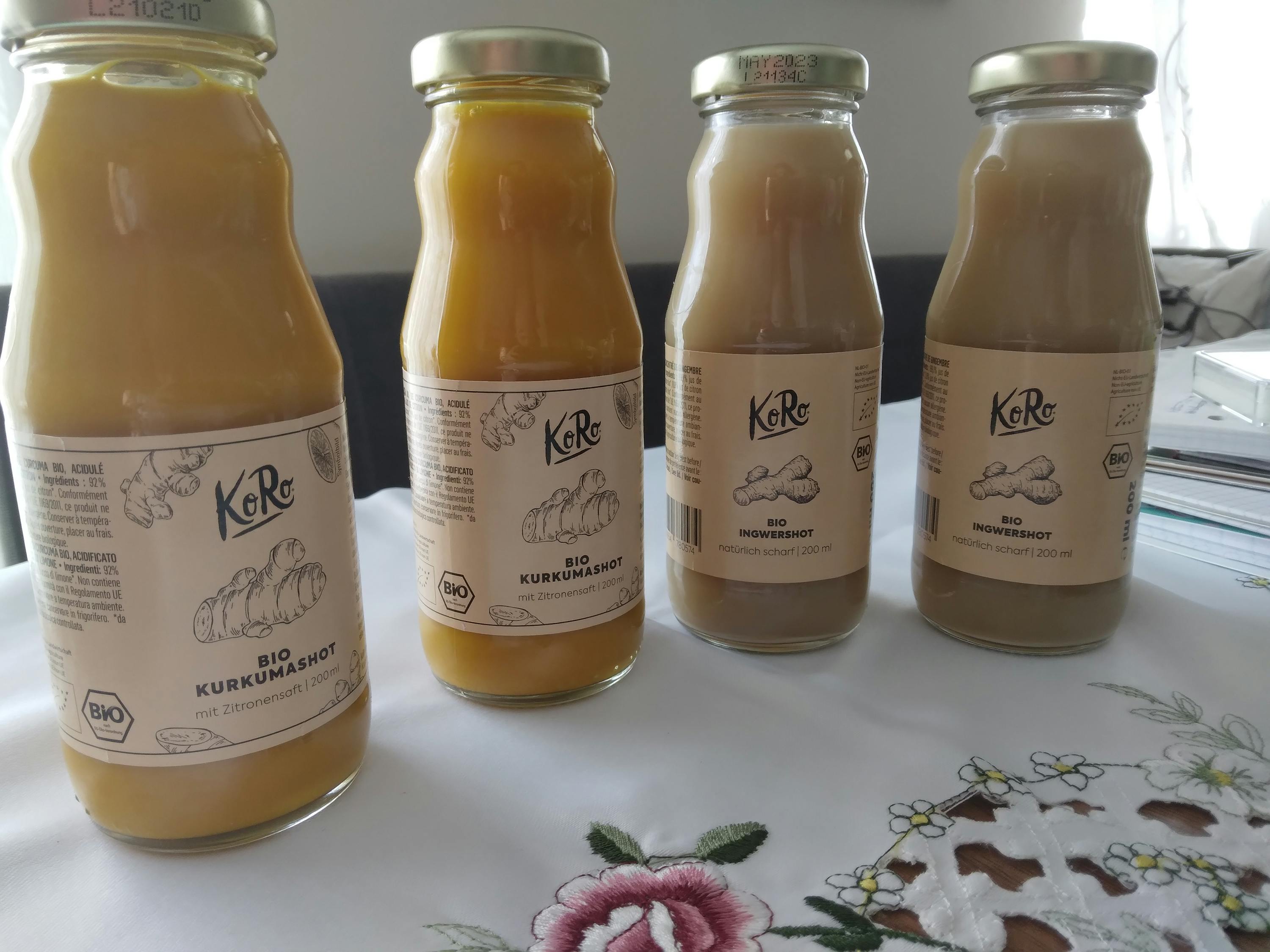 quatre bouteilles de boisson de curcuma et de gingembre sont assises sur une table