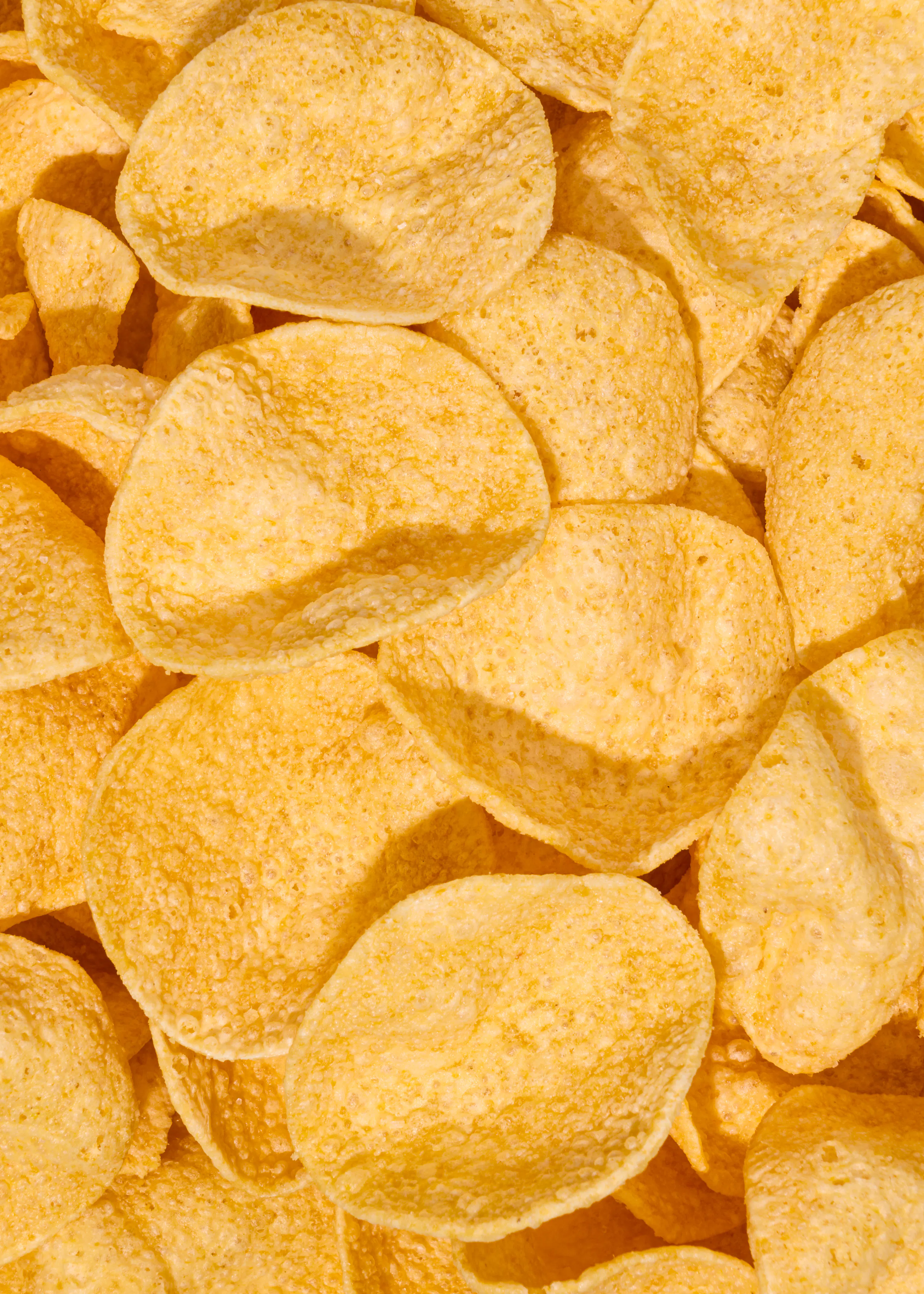 eine nahaufnahme von vielen goldgelben kartoffelchips, die dicht beieinander liegen.