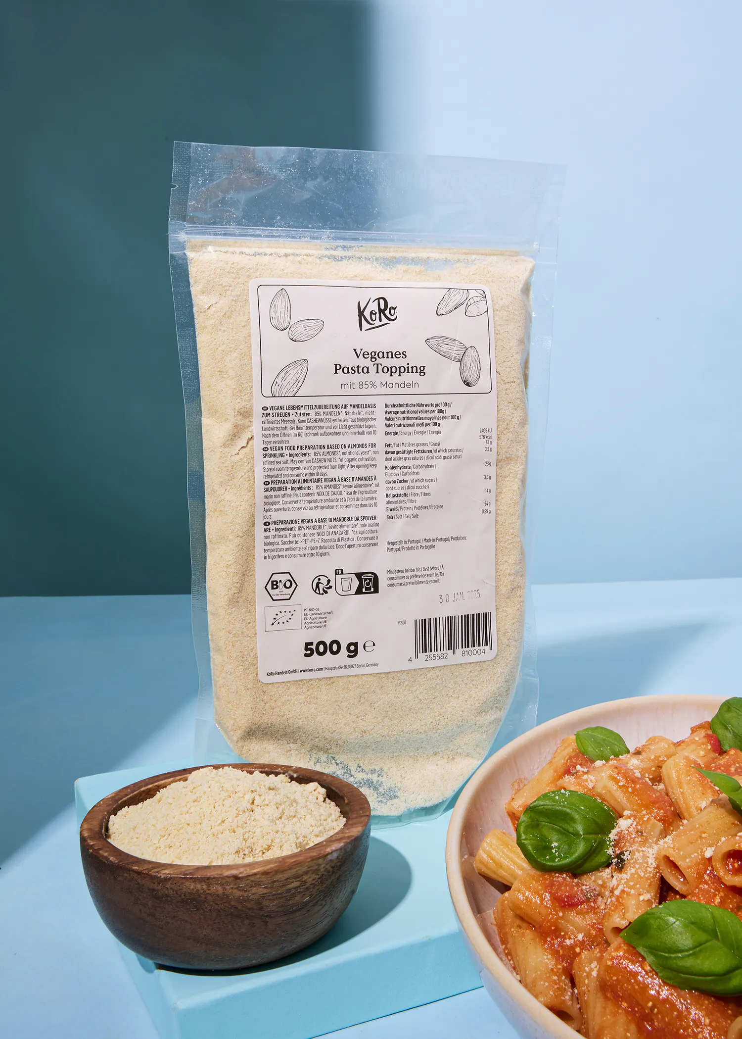 eine Tüte veganes Pasta Topping steht neben einer Schüssel mit Nudeln