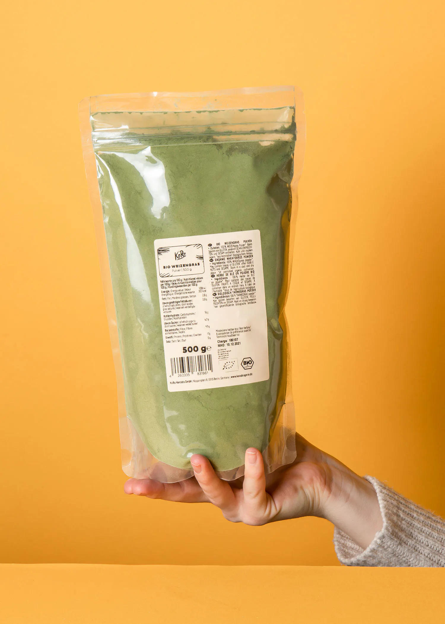 une personne tient un sac en plastique de 500g de poudre verte