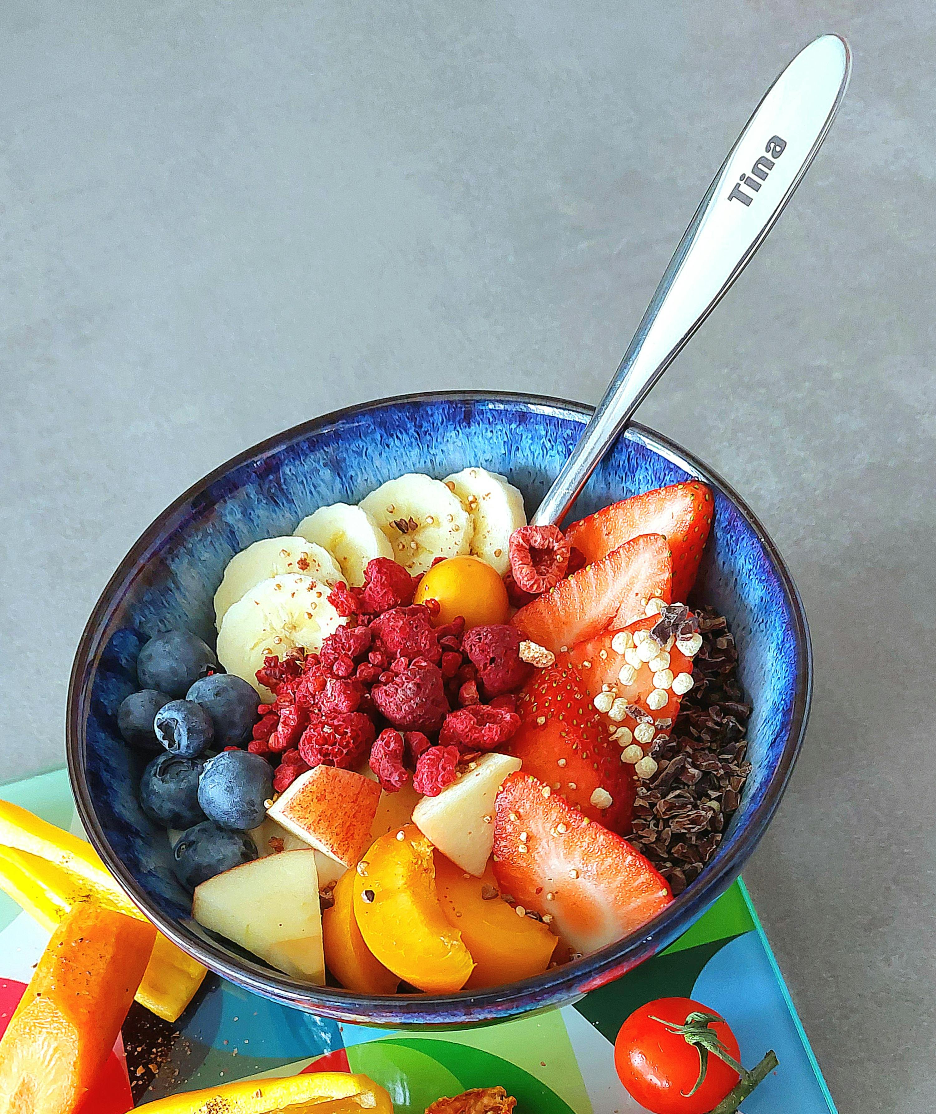 una ciotola piena di frutta e cereali con un cucchiaio che dice tina