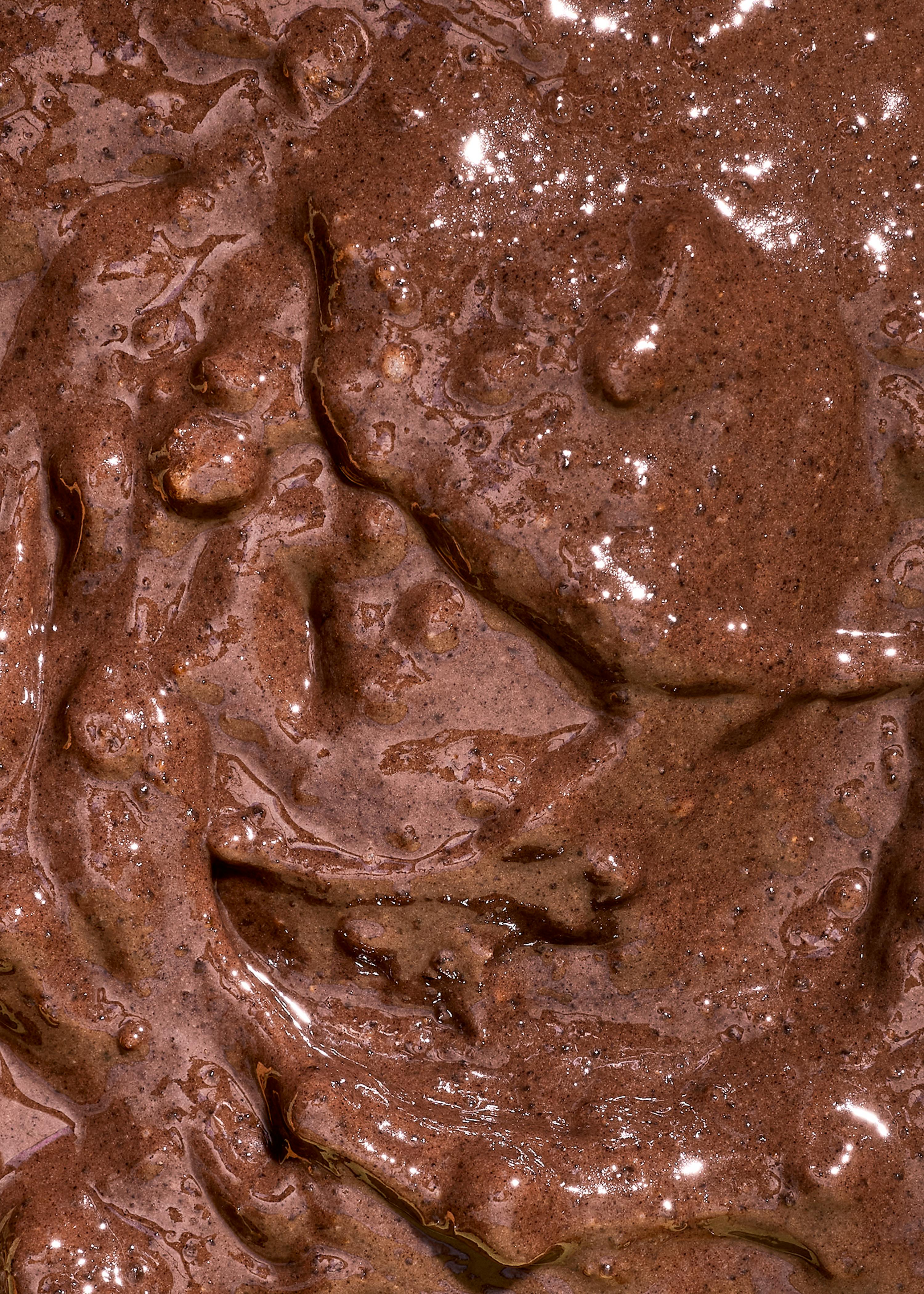 gros plan d'une substance brune épaisse et brillante, avec des reflets lumineux et une texture irrégulière.