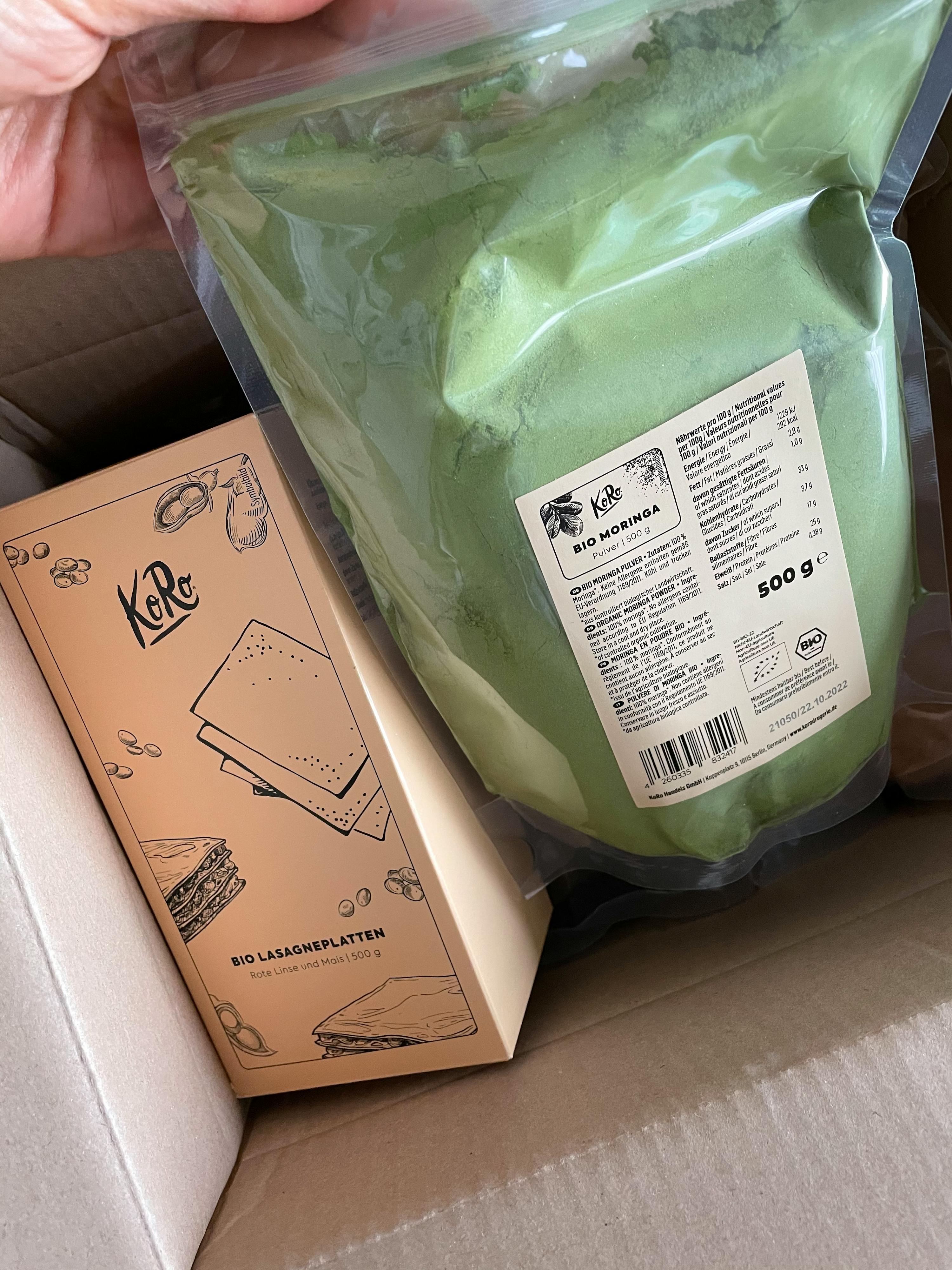 une personne tient un sac de poudre à côté d' une boîte de chocolat