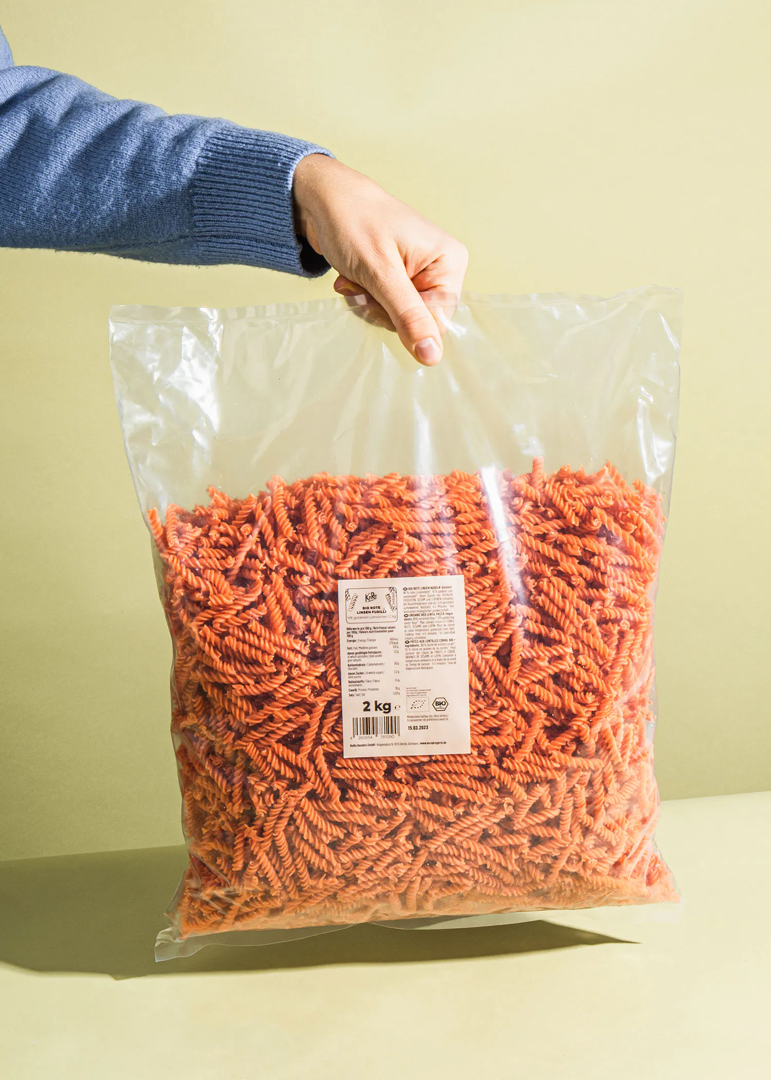 une personne tient un sac en plastique rempli de pâtes