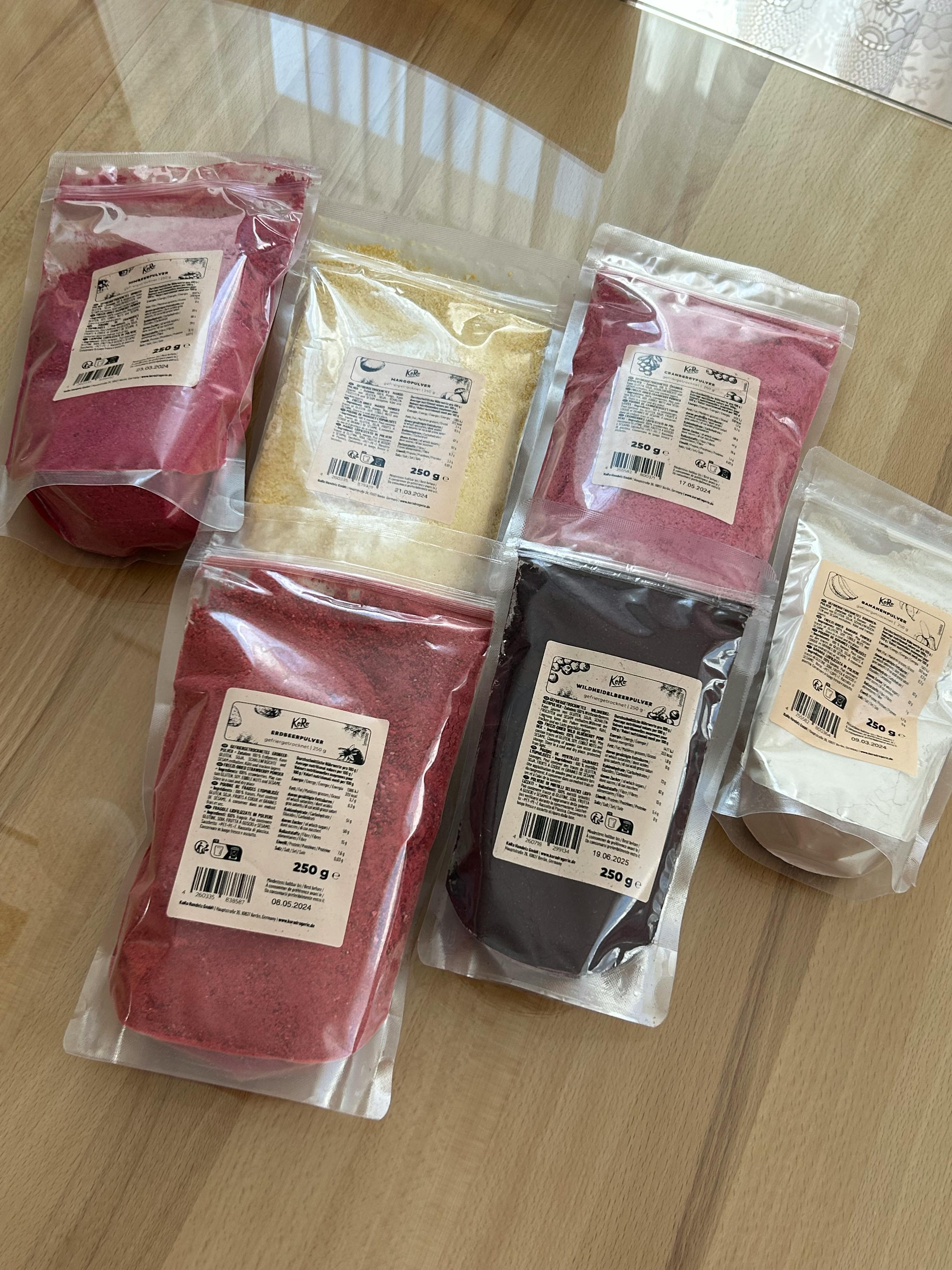 six bags of different colored powders are on a table