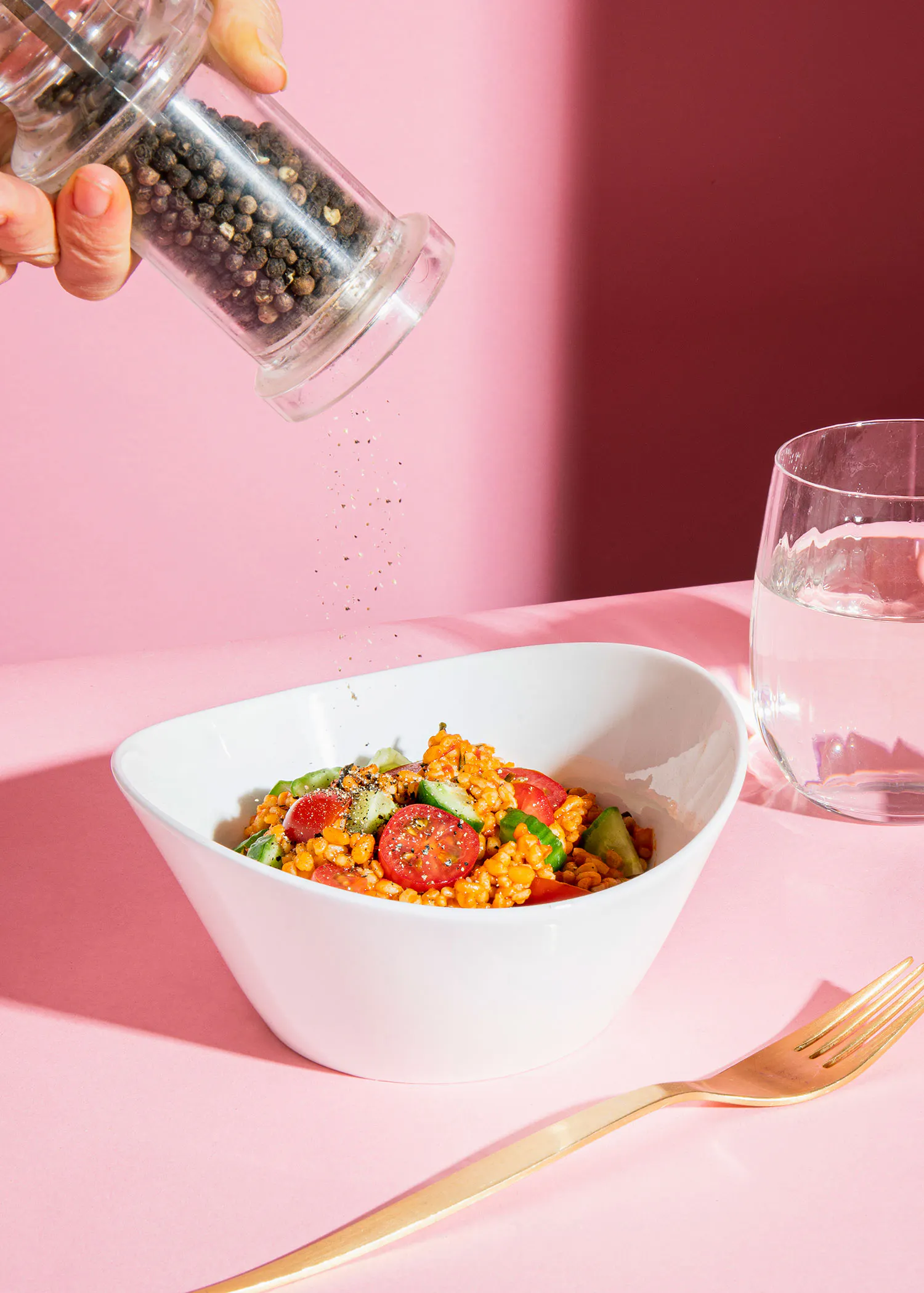 a person is pouring pepper into a bowl of food
