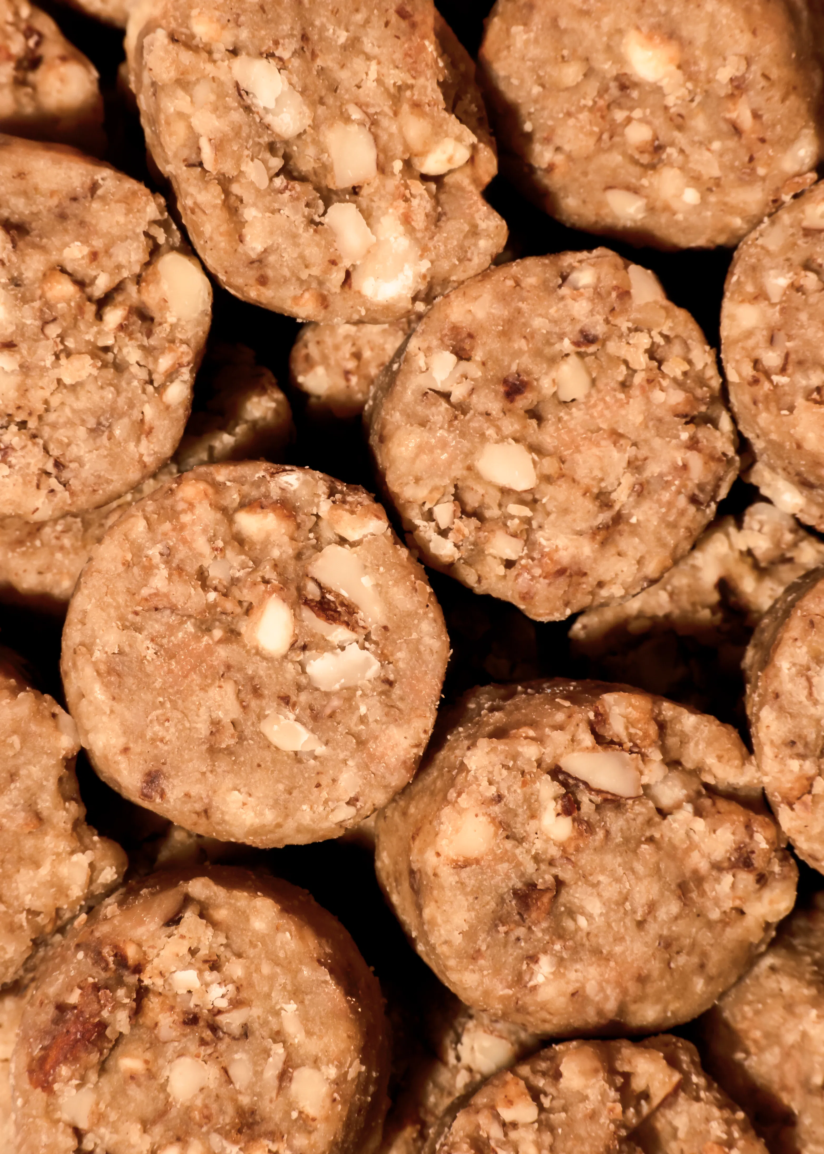 primer plano de varias galletas redondas de color marrón claro con trozos de nueces visibles.