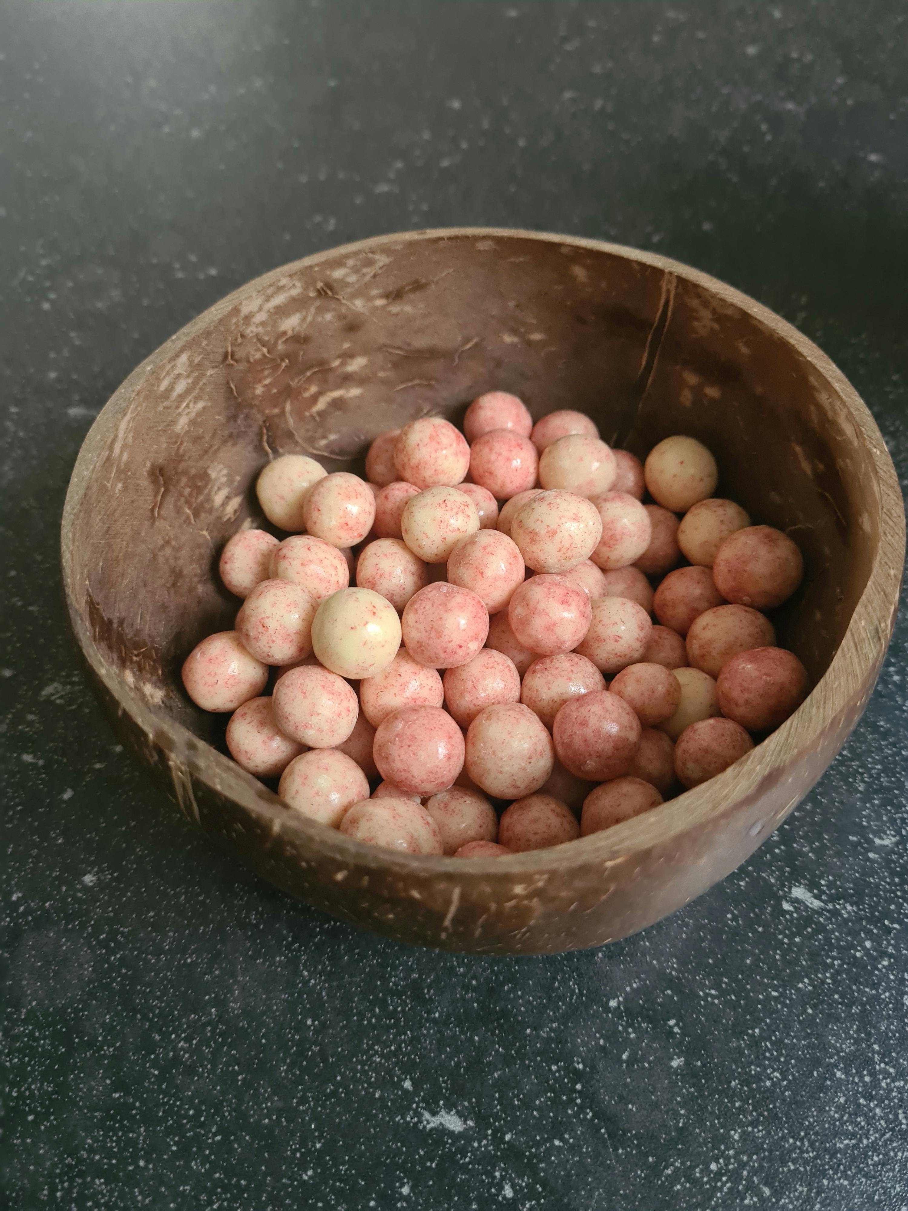una ciotola di legno piena di caramelle rosa e bianche