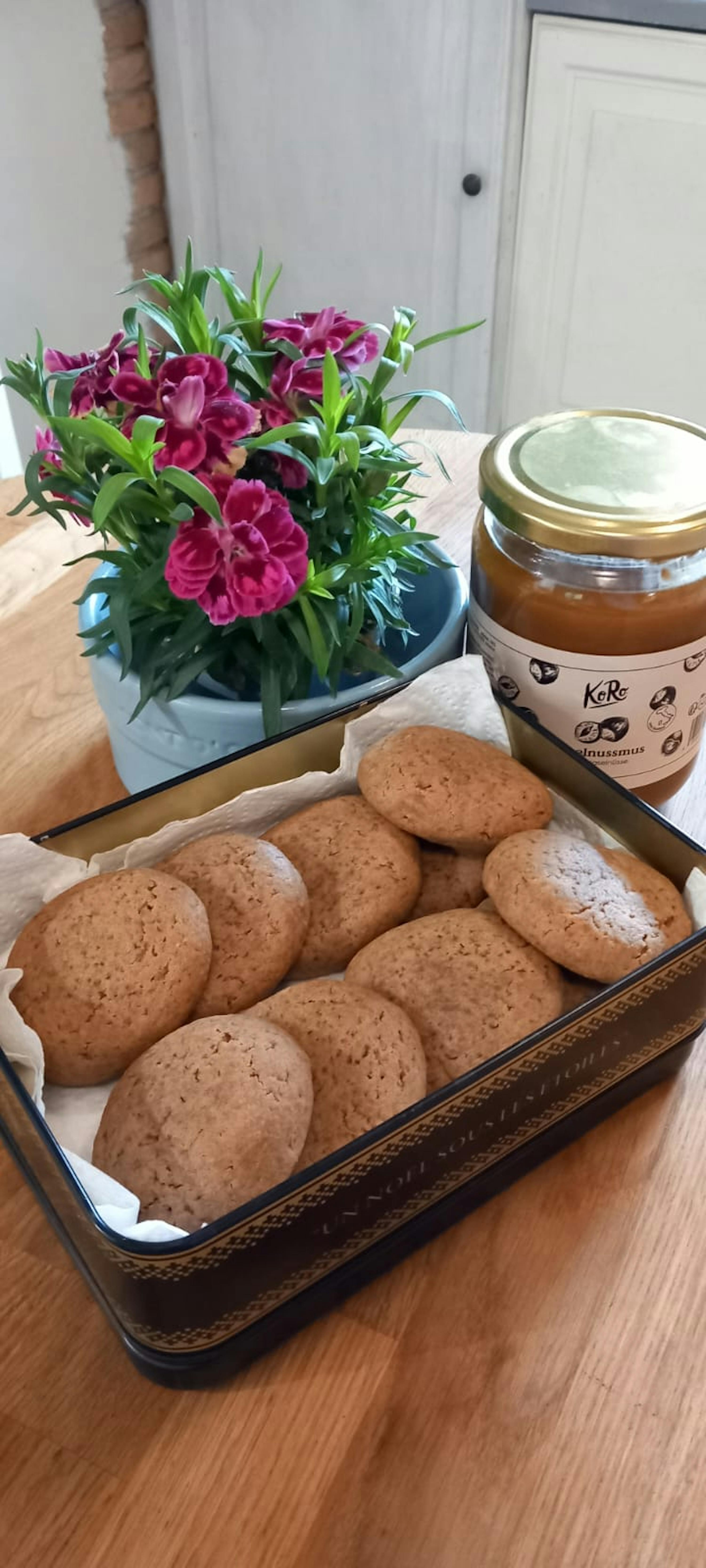 a tin filled with cookies next to a jar of kerri