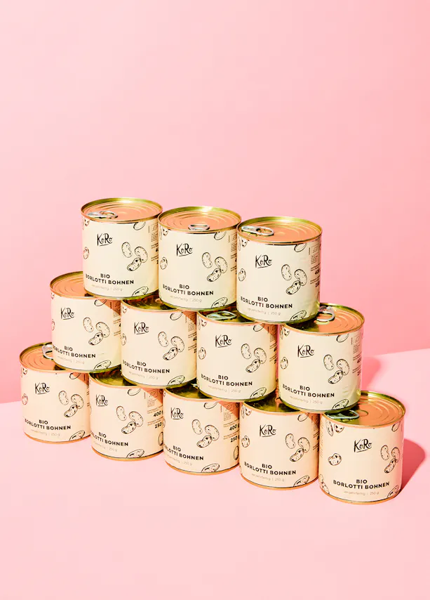 a stack of cans of bio sogliotti sohnen on a pink background