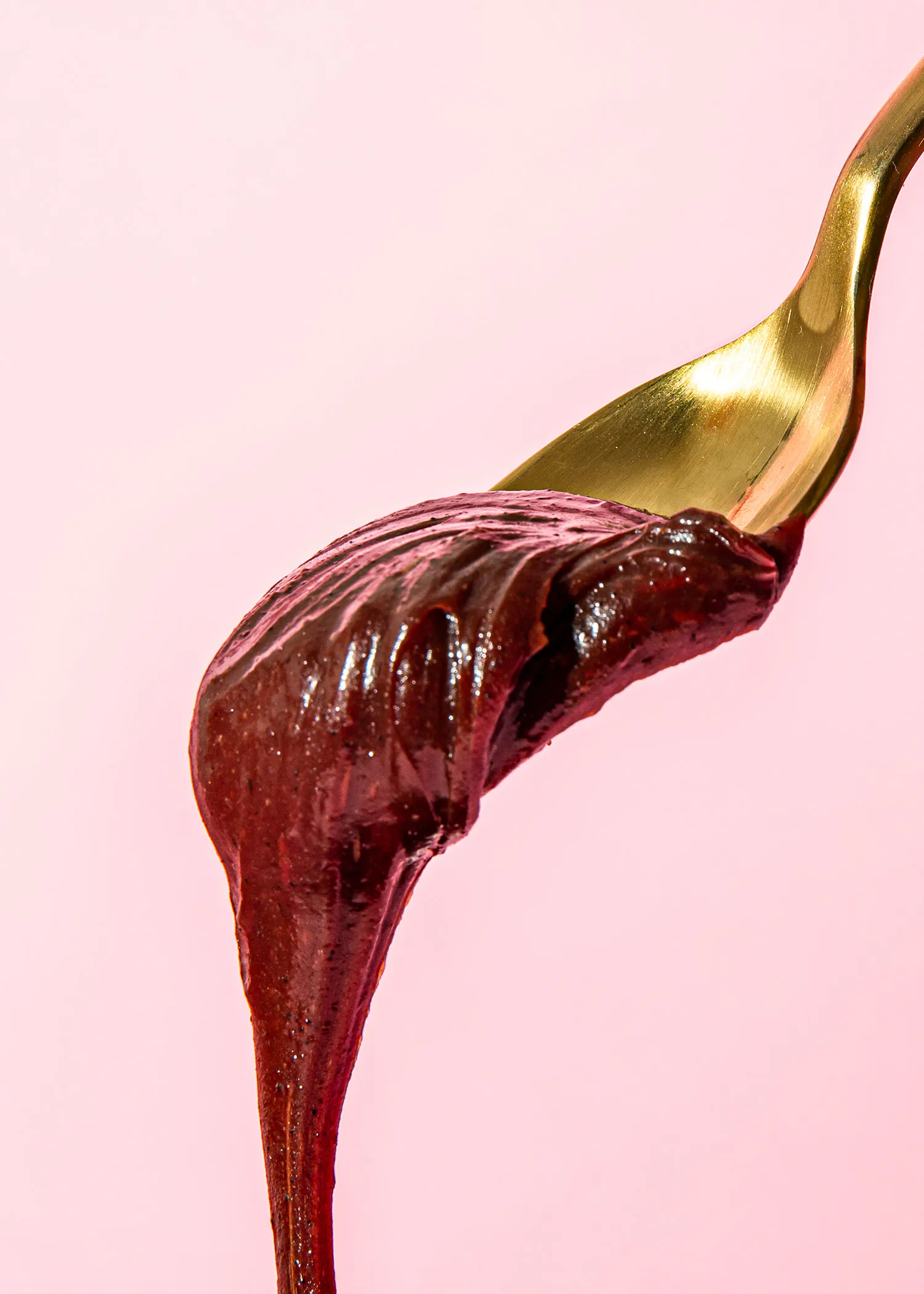 un gros plan d' une cuillère remplie de chocolat sur fond rose