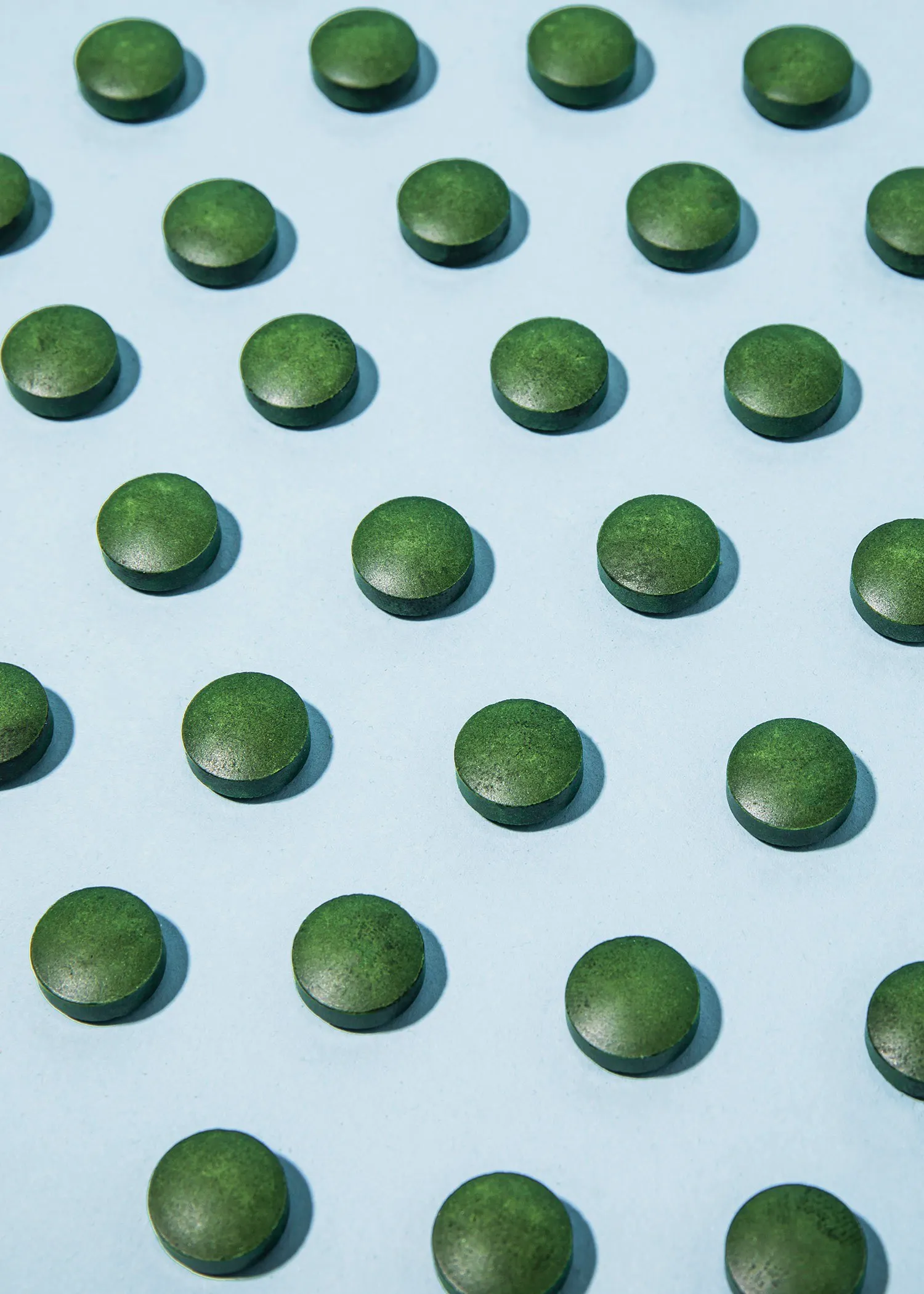 des pilules vertes sont disposées en cercles sur un fond bleu