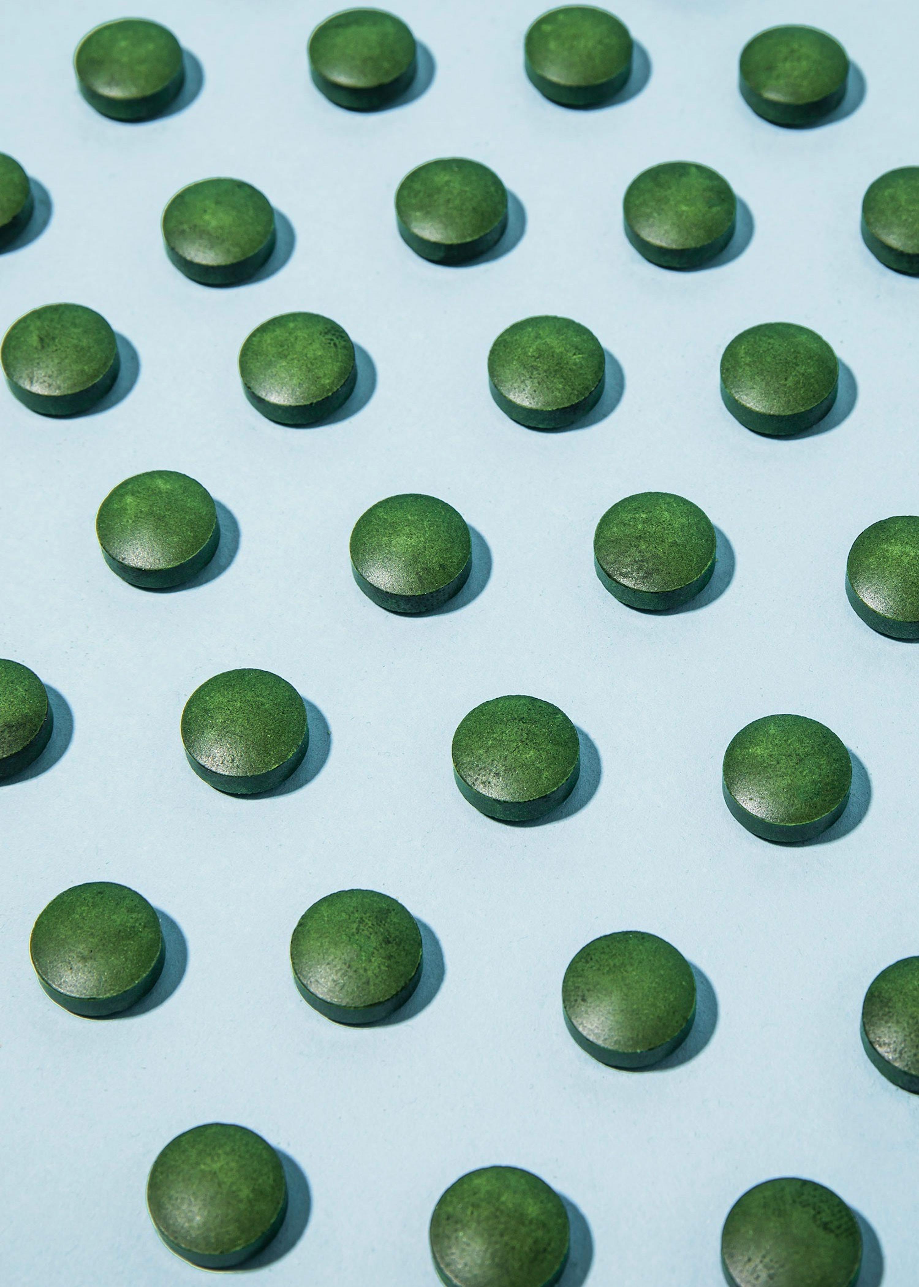 rows of green pills on a blue surface