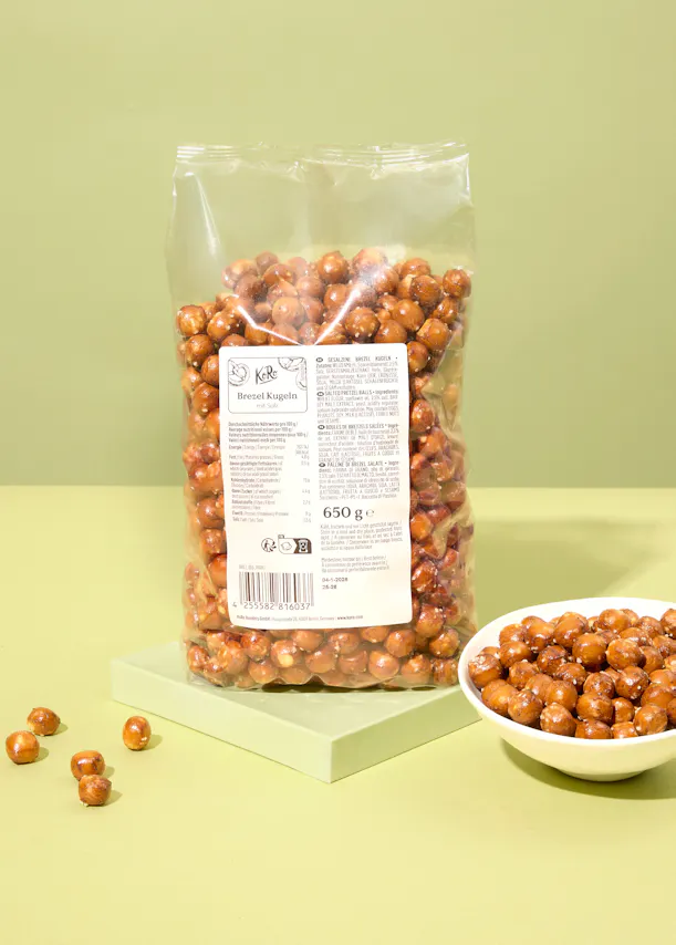 eine Tüte gebratene Haselnüsse steht neben einer Schüssel Haselnüsse