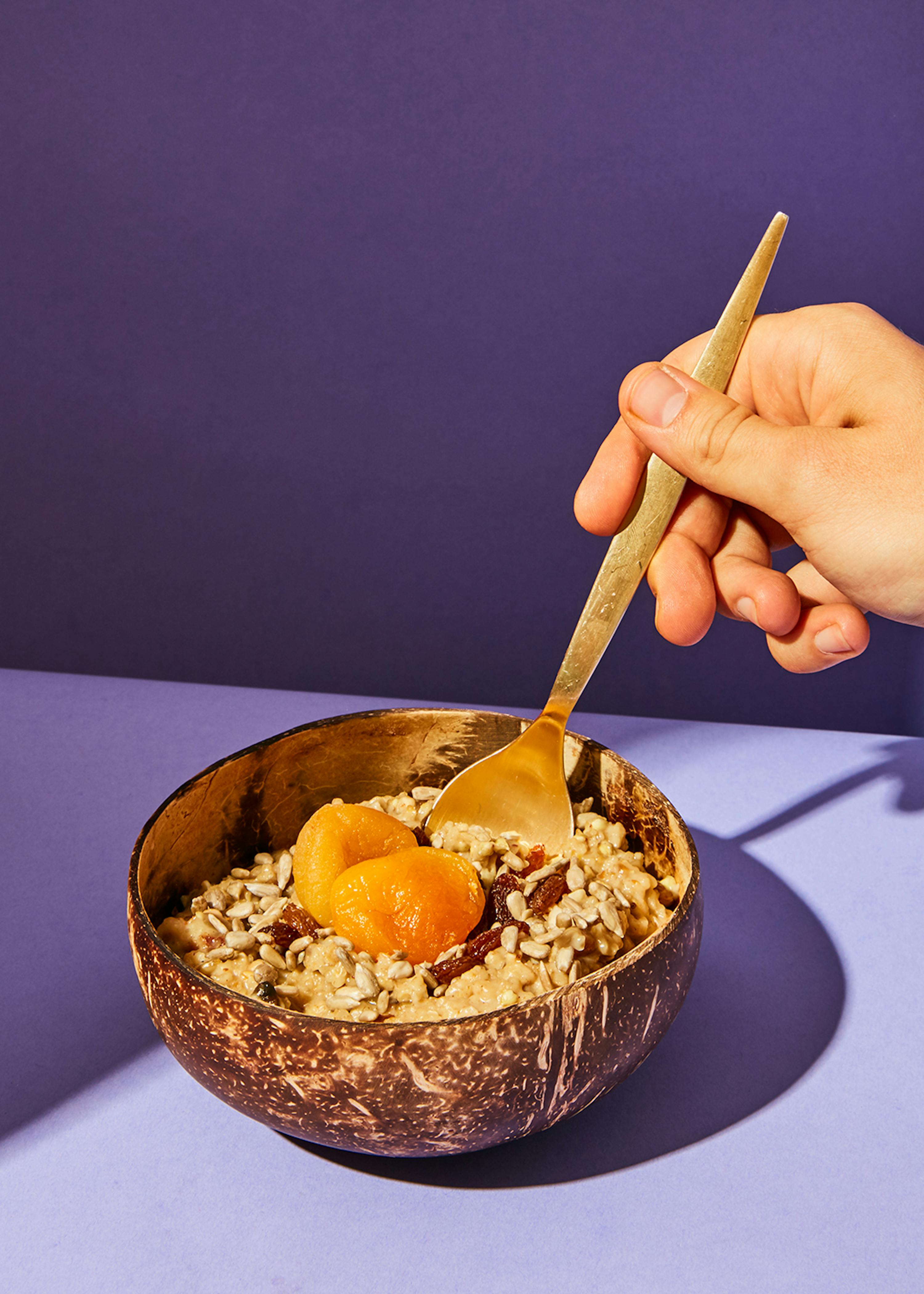 una persona sta mangiando una ciotola di avena con un cucchiaio
