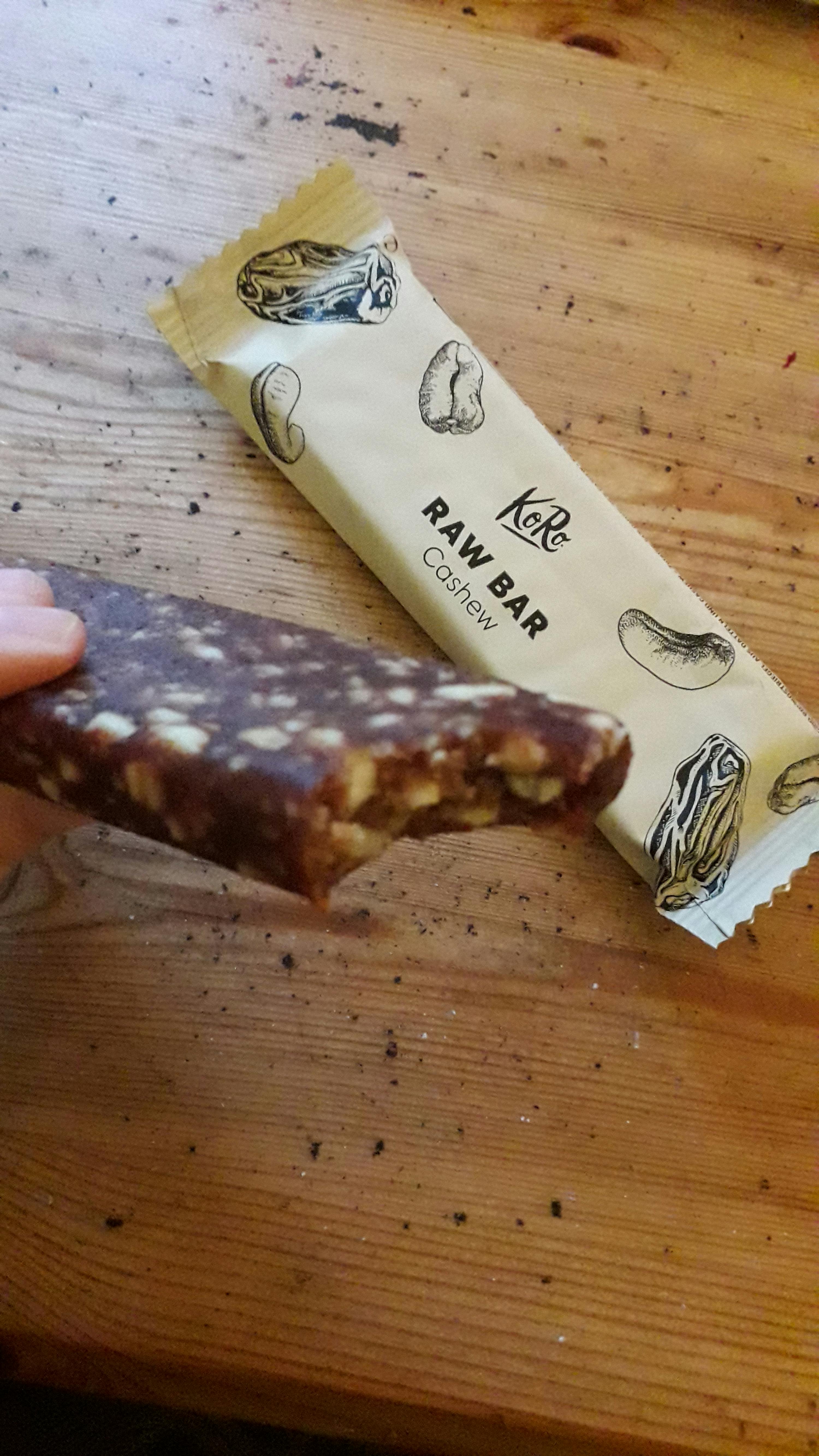 une personne tient une barre de raw cashew avec une bouchée sortie