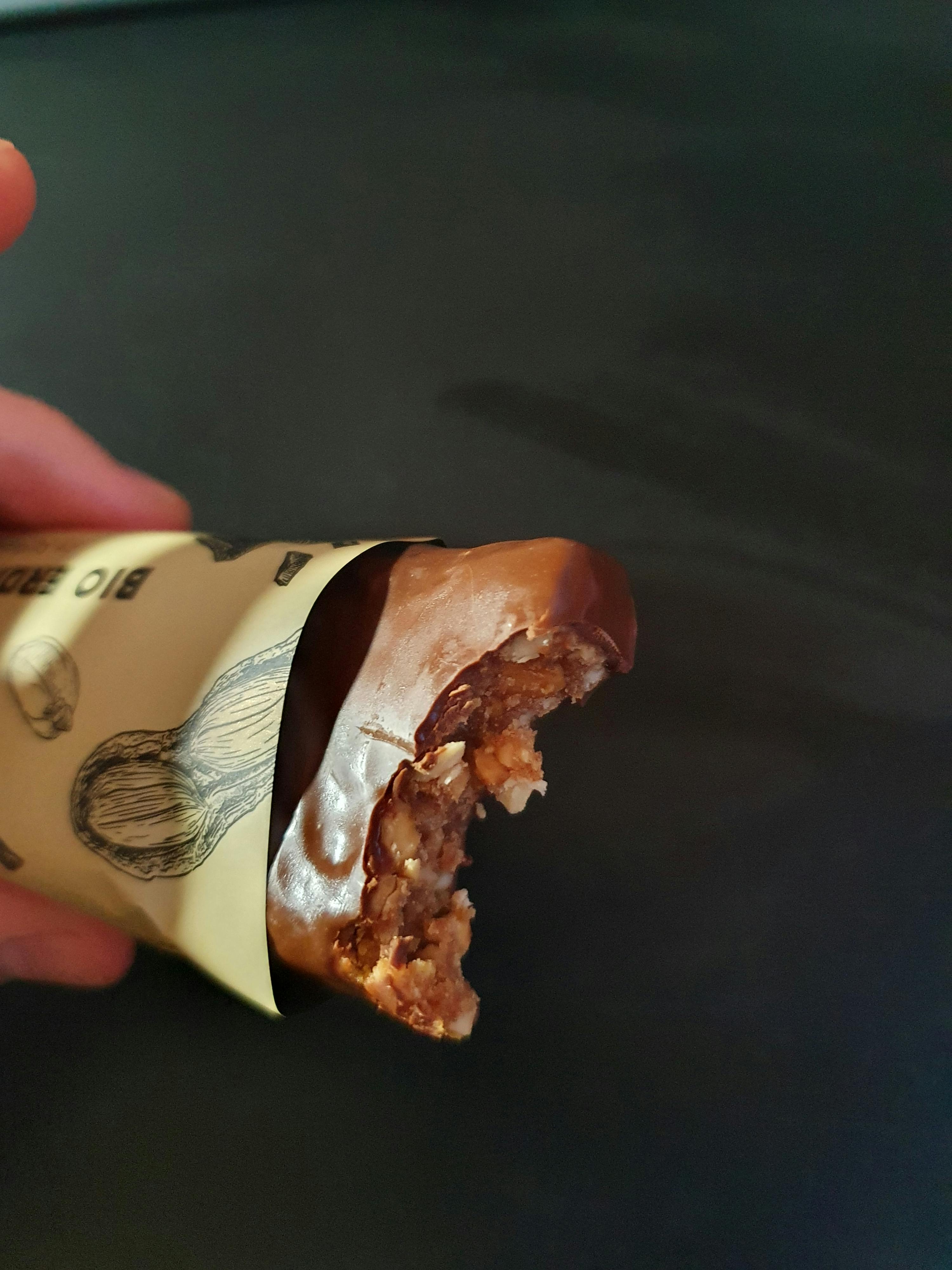 une personne tient une barre de chocolat bio avec une morsure prise dedans