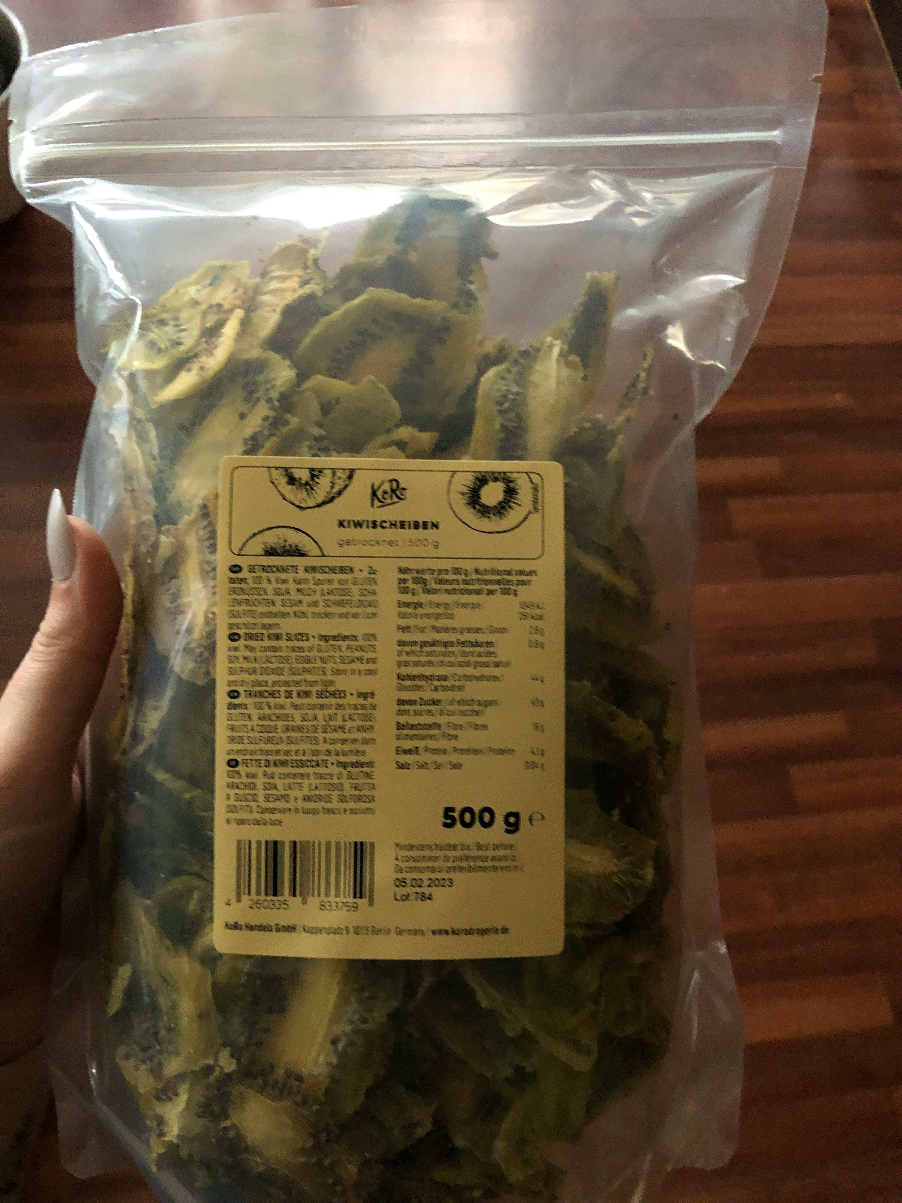Eine Person hält einen Plastikbeutel mit kiwichips in der Hand
