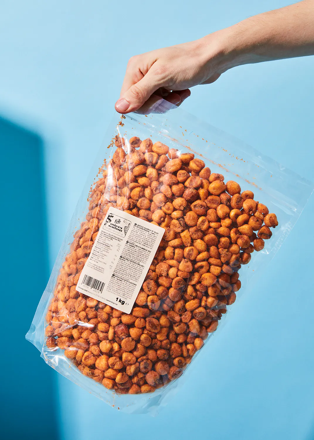 a person is holding a bag of corn on the cob on a blue background