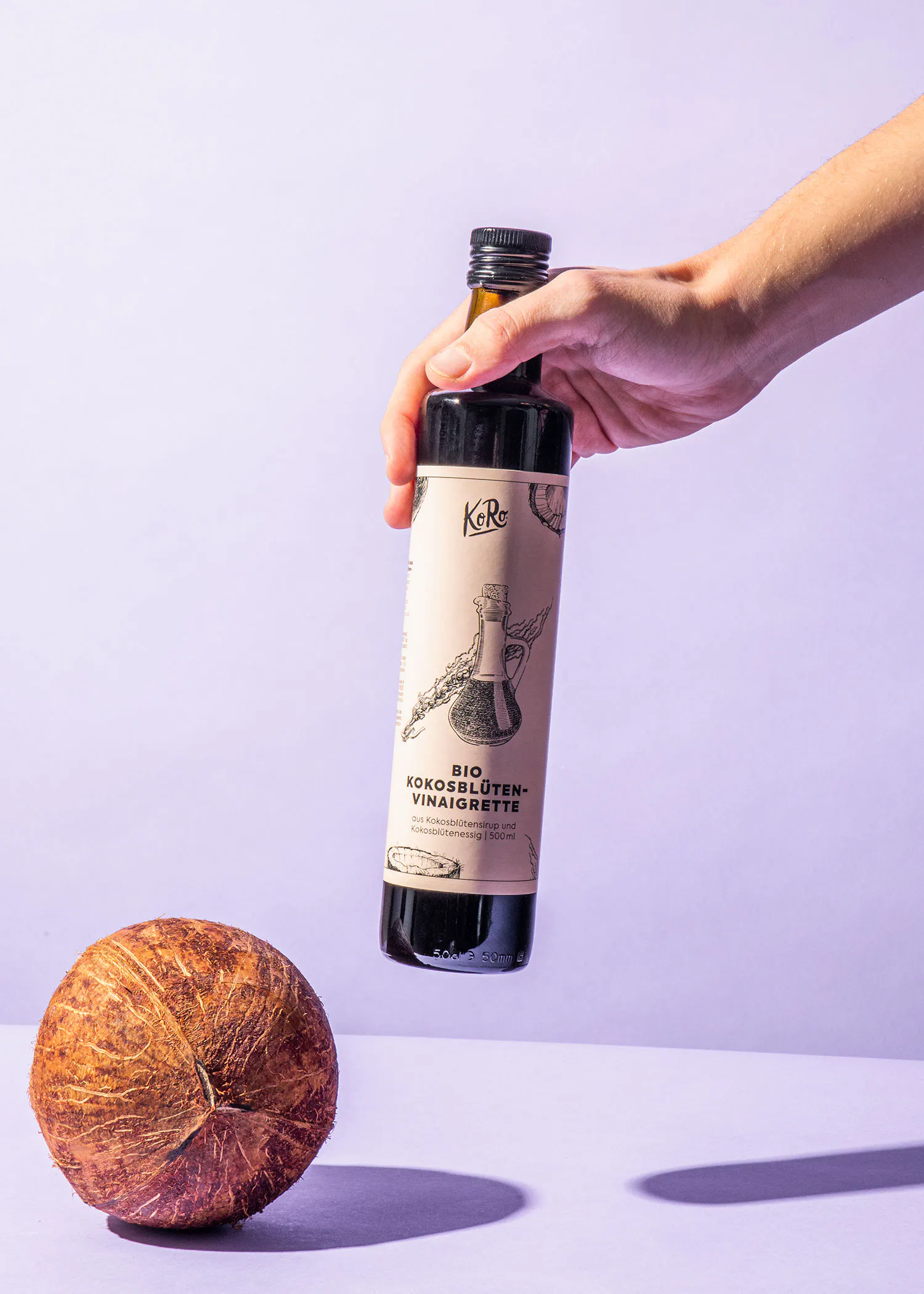 Eine Person hält eine Flasche Kokosblüten-Eistee in der Hand