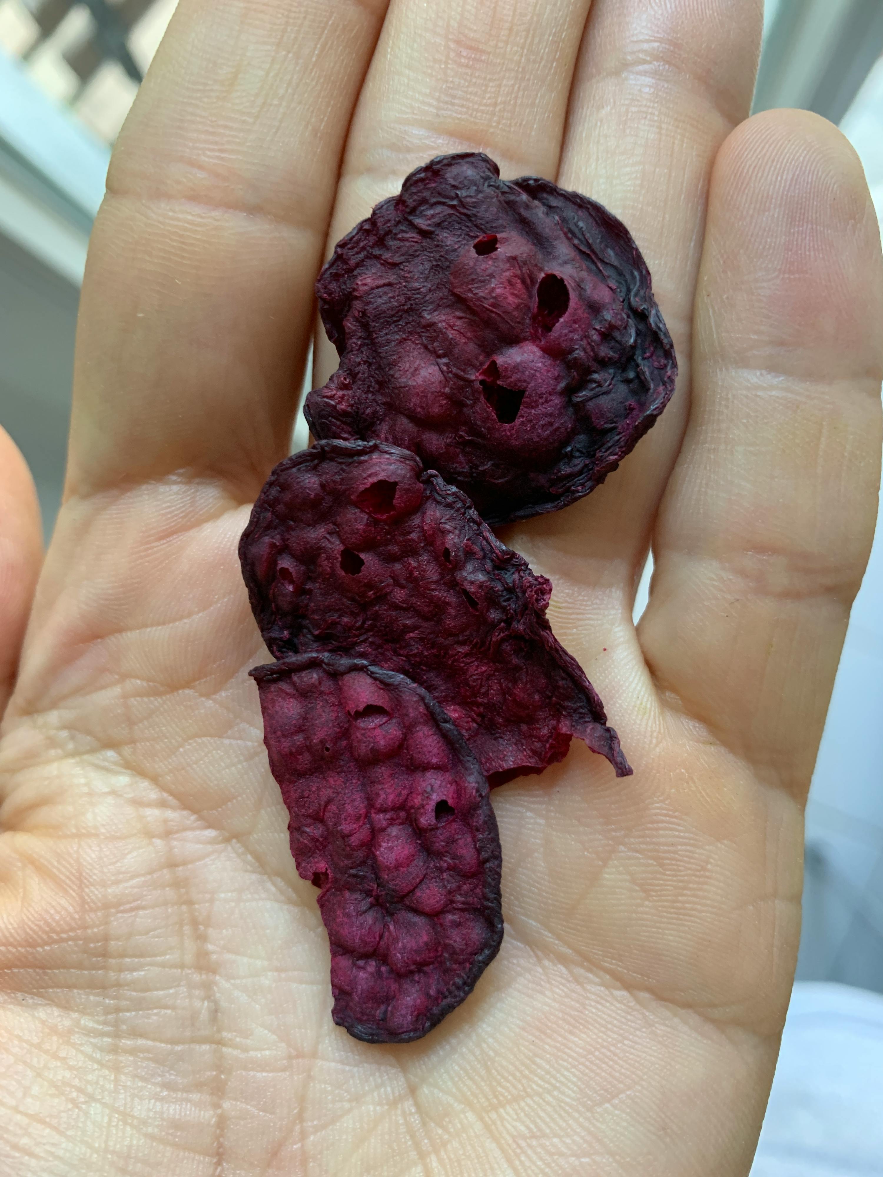 eine Person hält in der Hand drei kleine rote Früchte