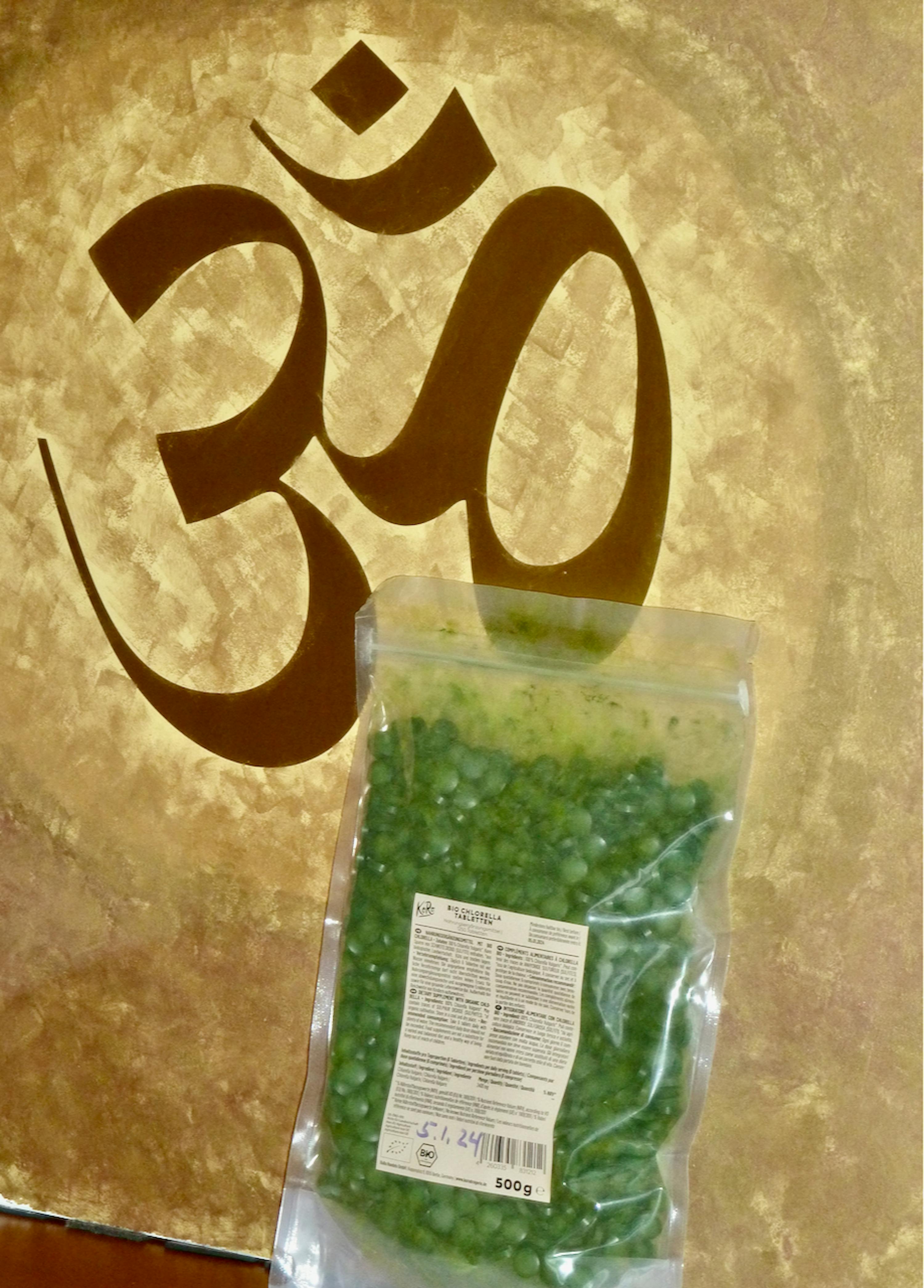 un sac de pois verts est posé sur une table avec un symbole om en arrière-plan