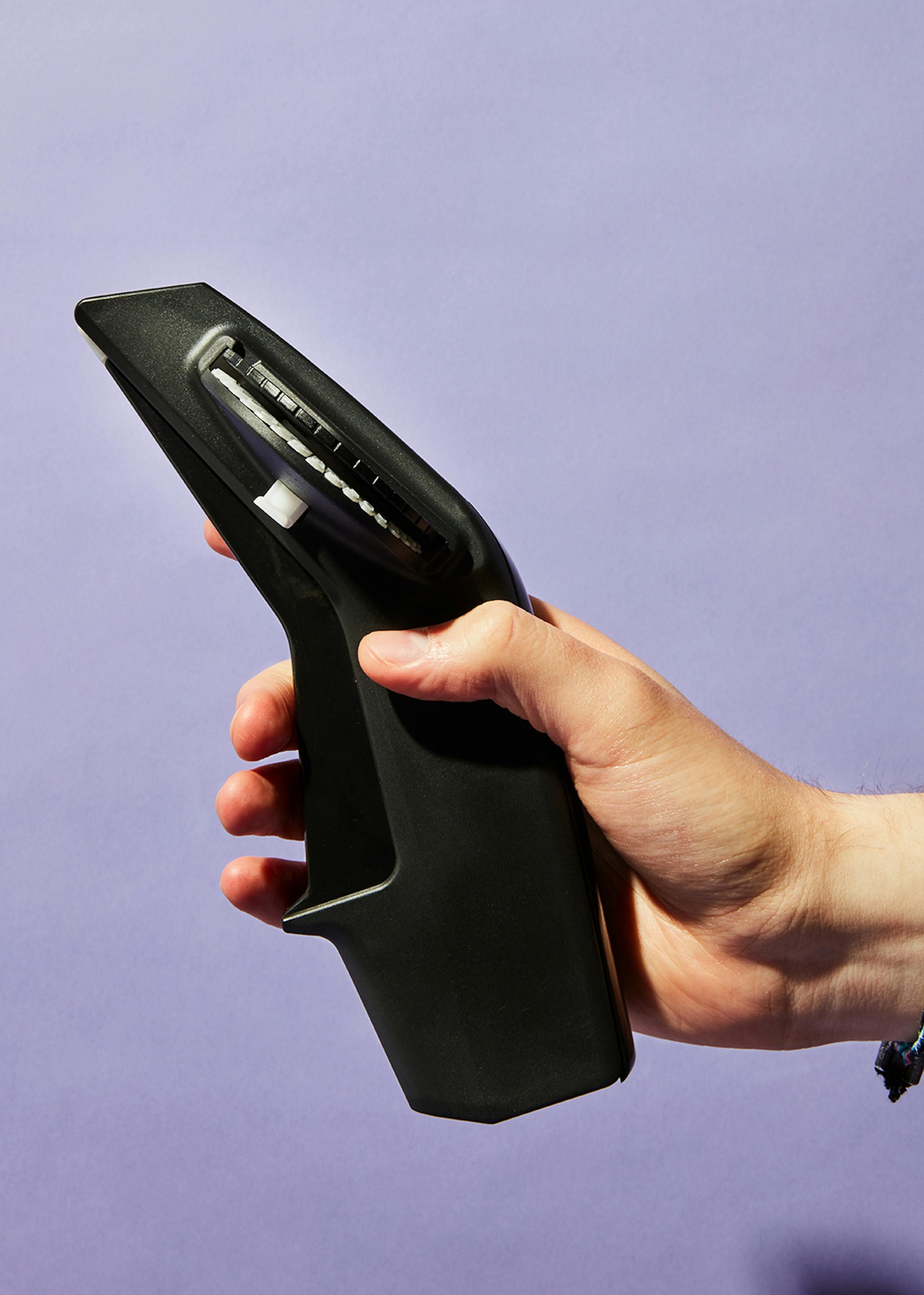 a person is holding a black object with a purple background