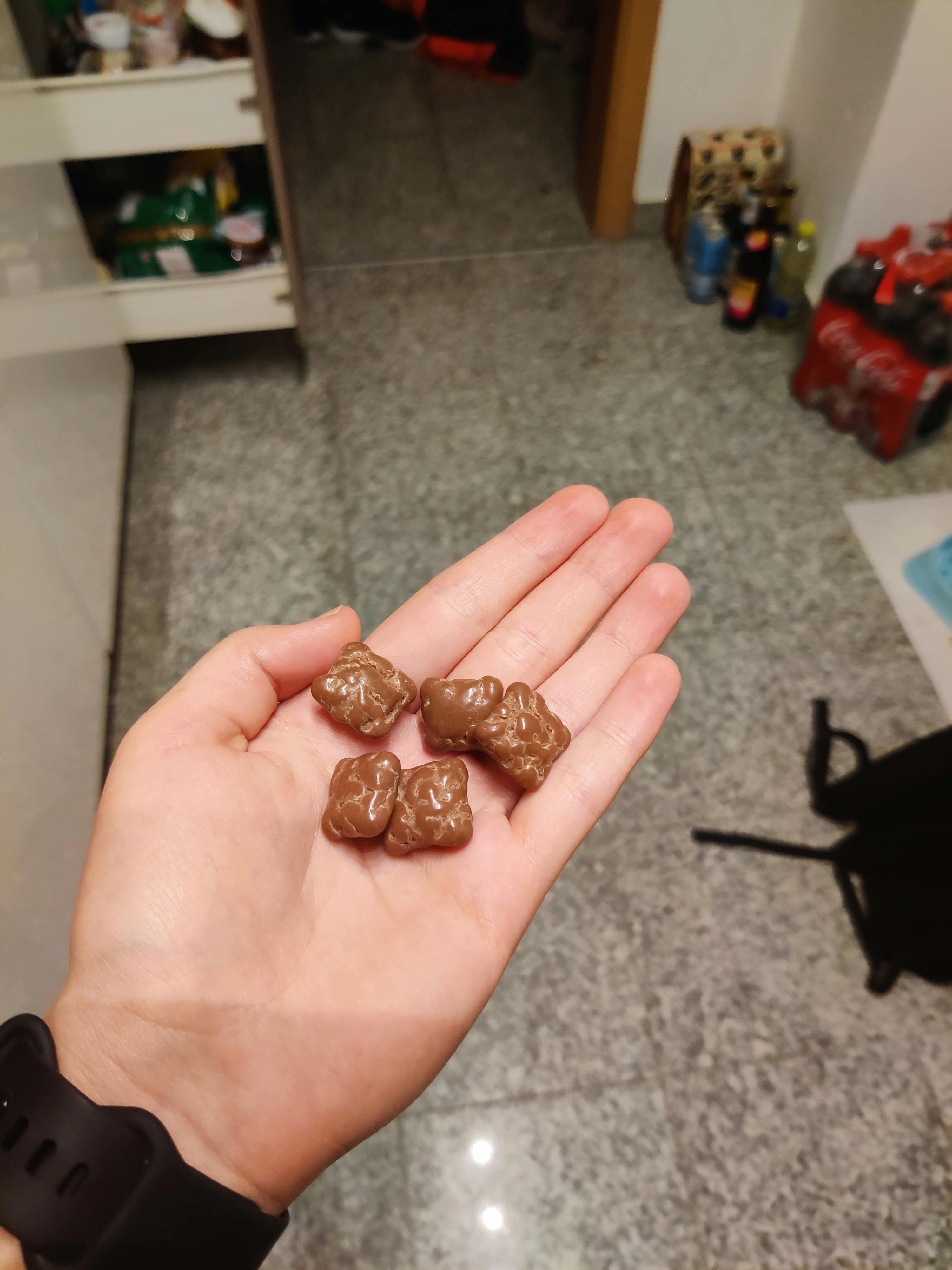 a person holding four chocolate bears in their hand