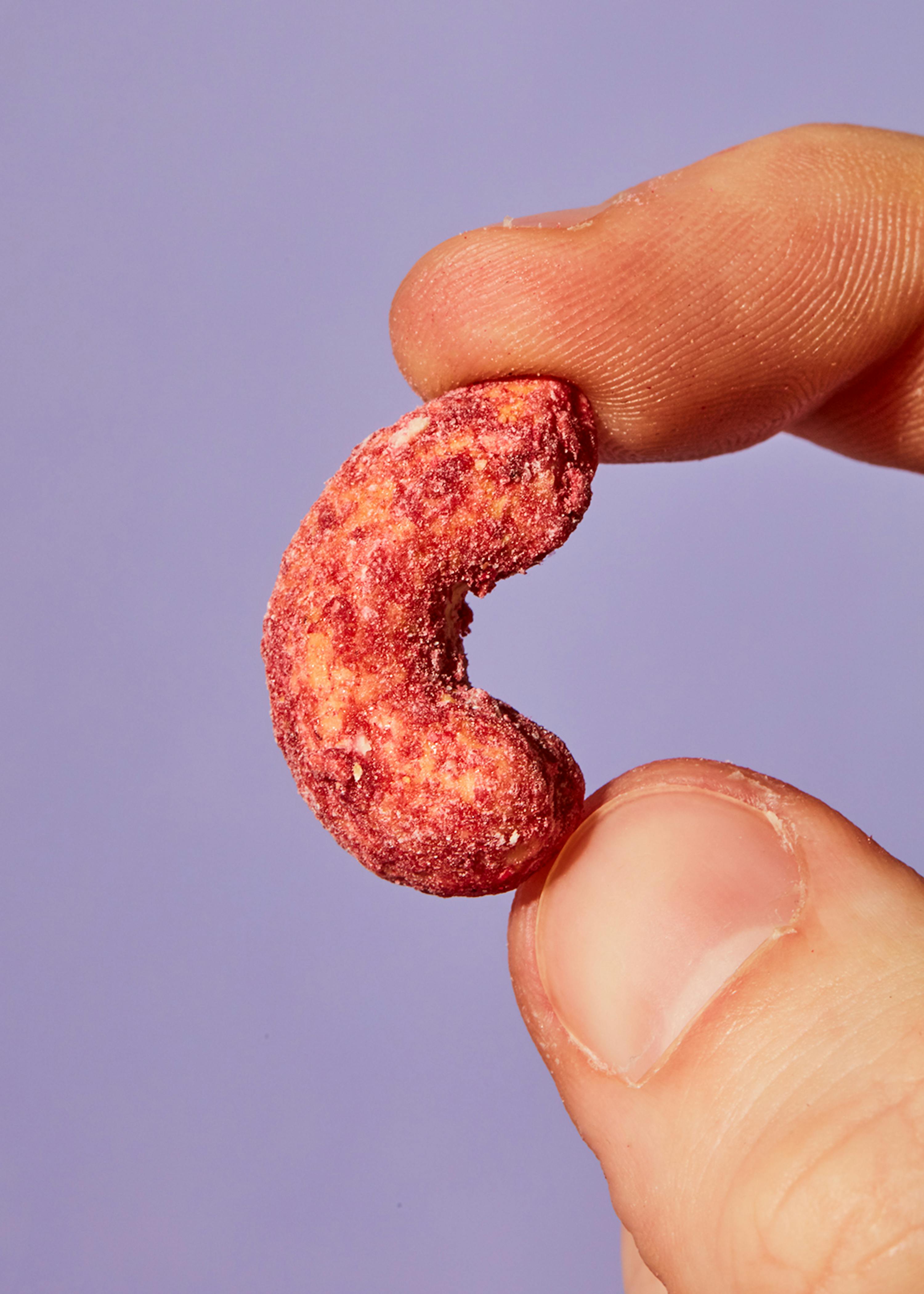 un primo piano di una persona che tiene in mano un biscotto rosa