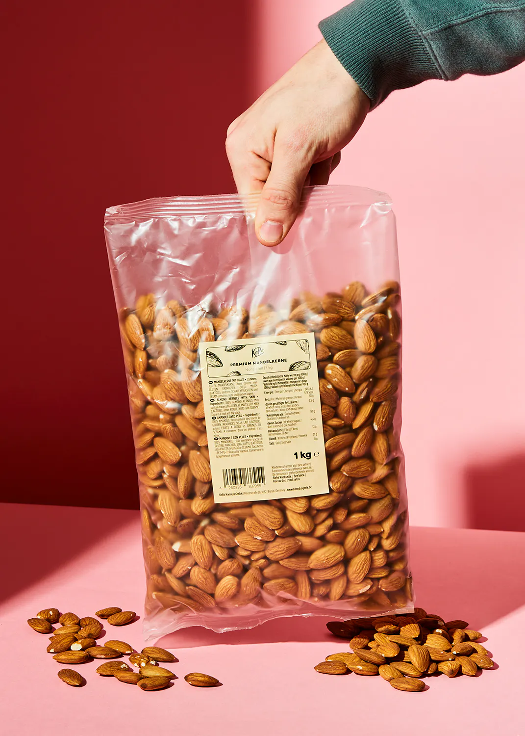 une personne tient un sac de noix d' amandes sur une table rose