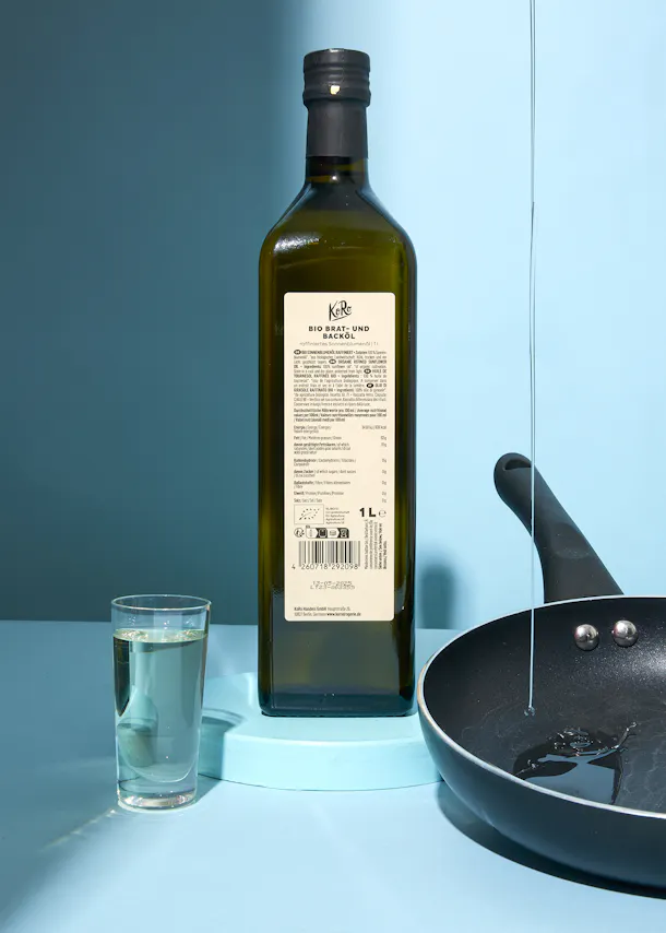 une bouteille d' huile d' olive est assise à côté d' une poêle