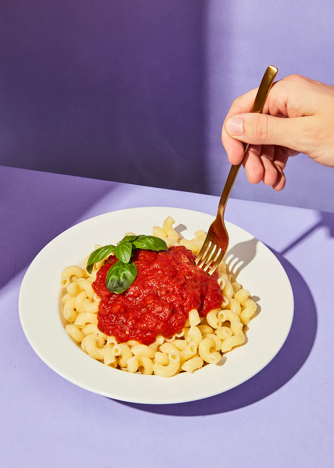 une personne mange des pâtes avec une fourchette sur une assiette